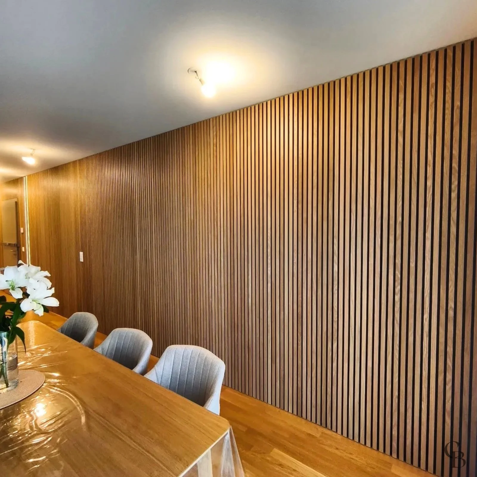 Habillage mural acoustique en lames de chêne vernis conçu et posé sur mesure par Concept & Bois à Genève.