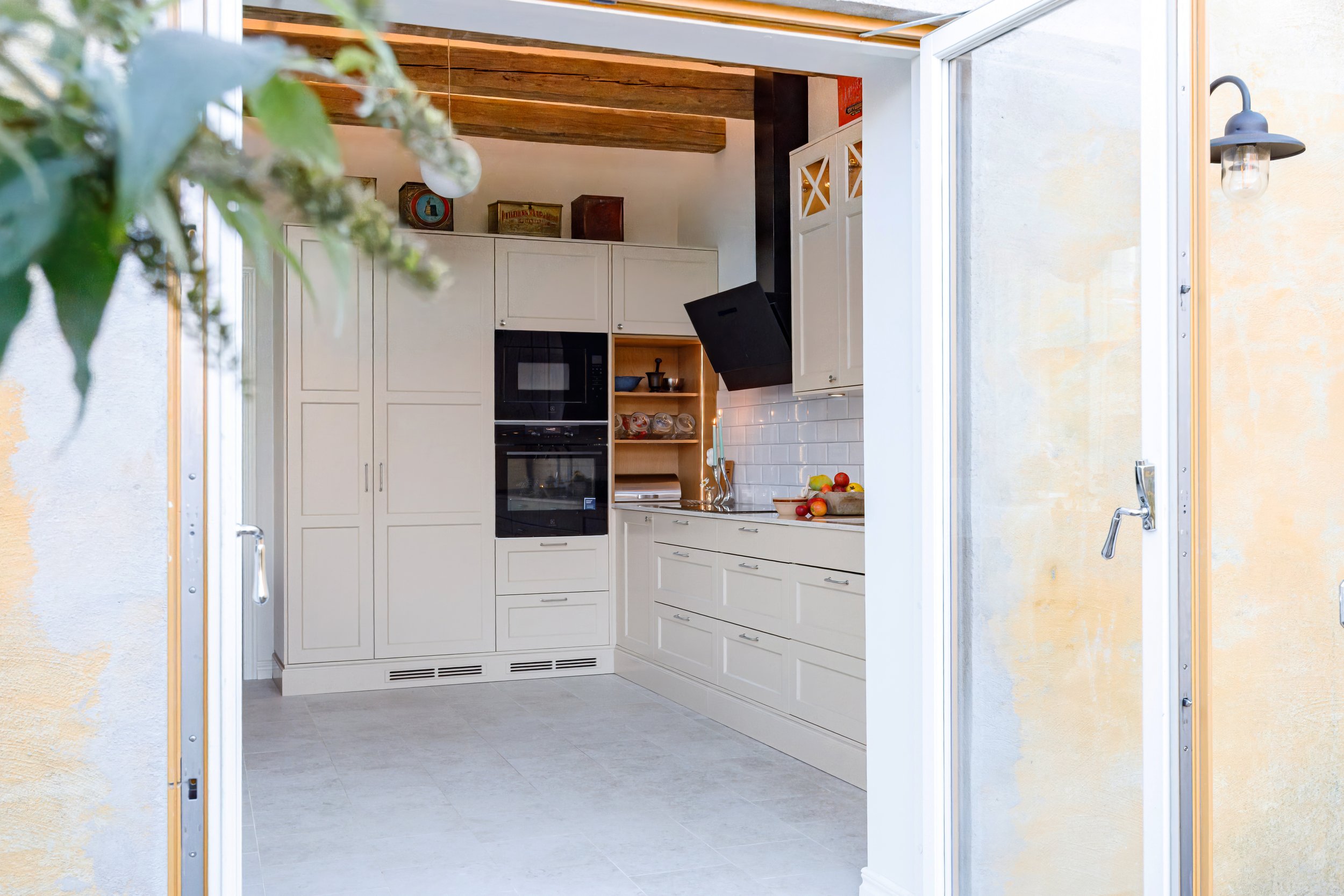 Vy in i platsbyggt kök från Smedstorps Snickeri sett genom öppen dörr med naturligt ljus.