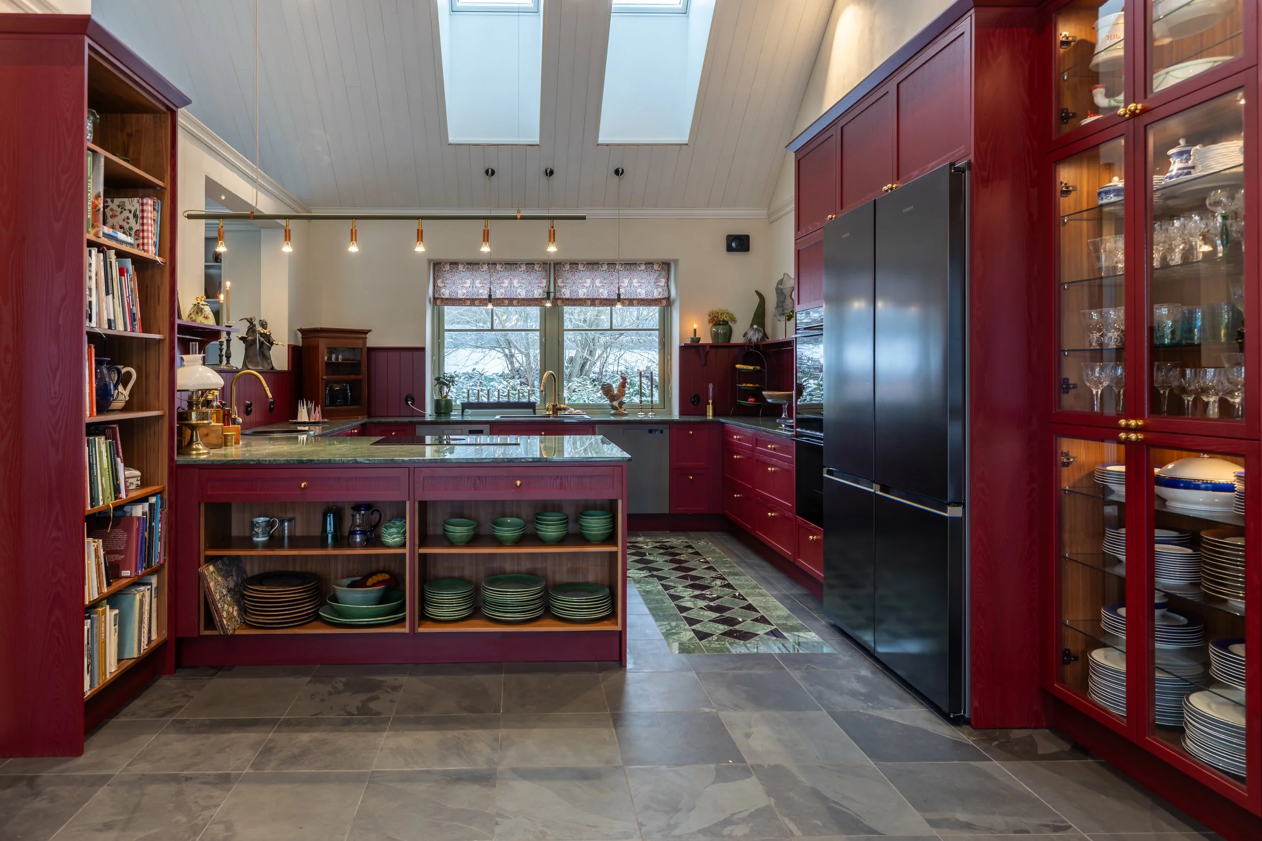 Platsbyggt rött kök med köksö från Smedstorps Snickeri och takfönster som ger naturligt ljus.