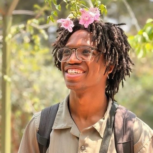 A man standing outdoors with flowers in his hair