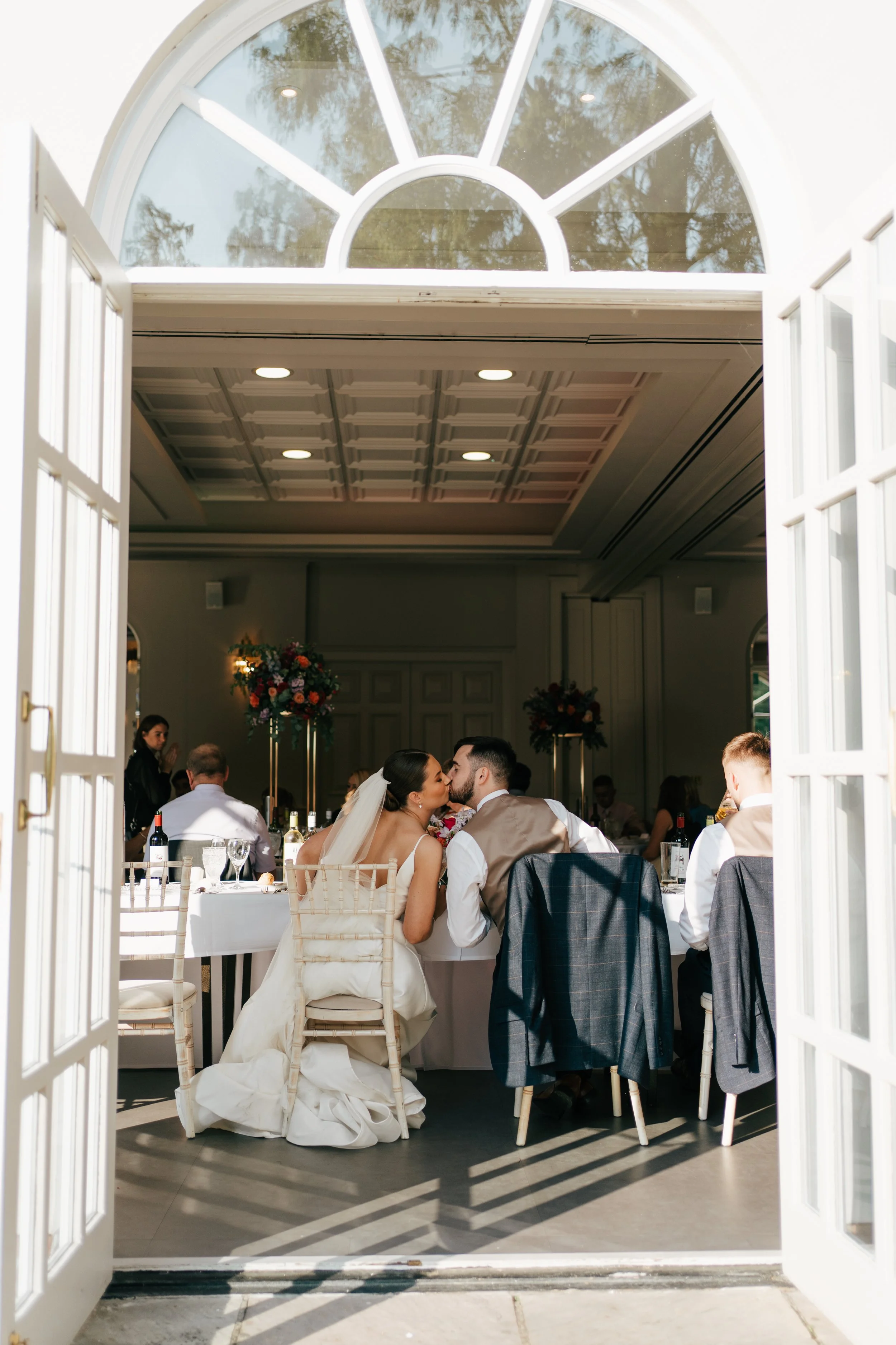Bride and groom kissing during their wedding breakfast