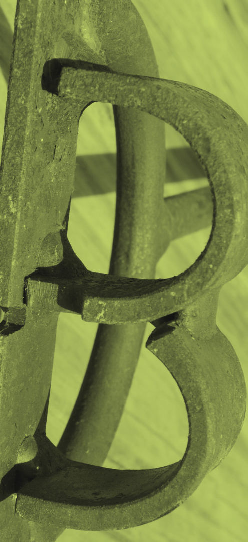Close-up of a vintage metal fireplace grate with a curved design, placed on a wooden surface.