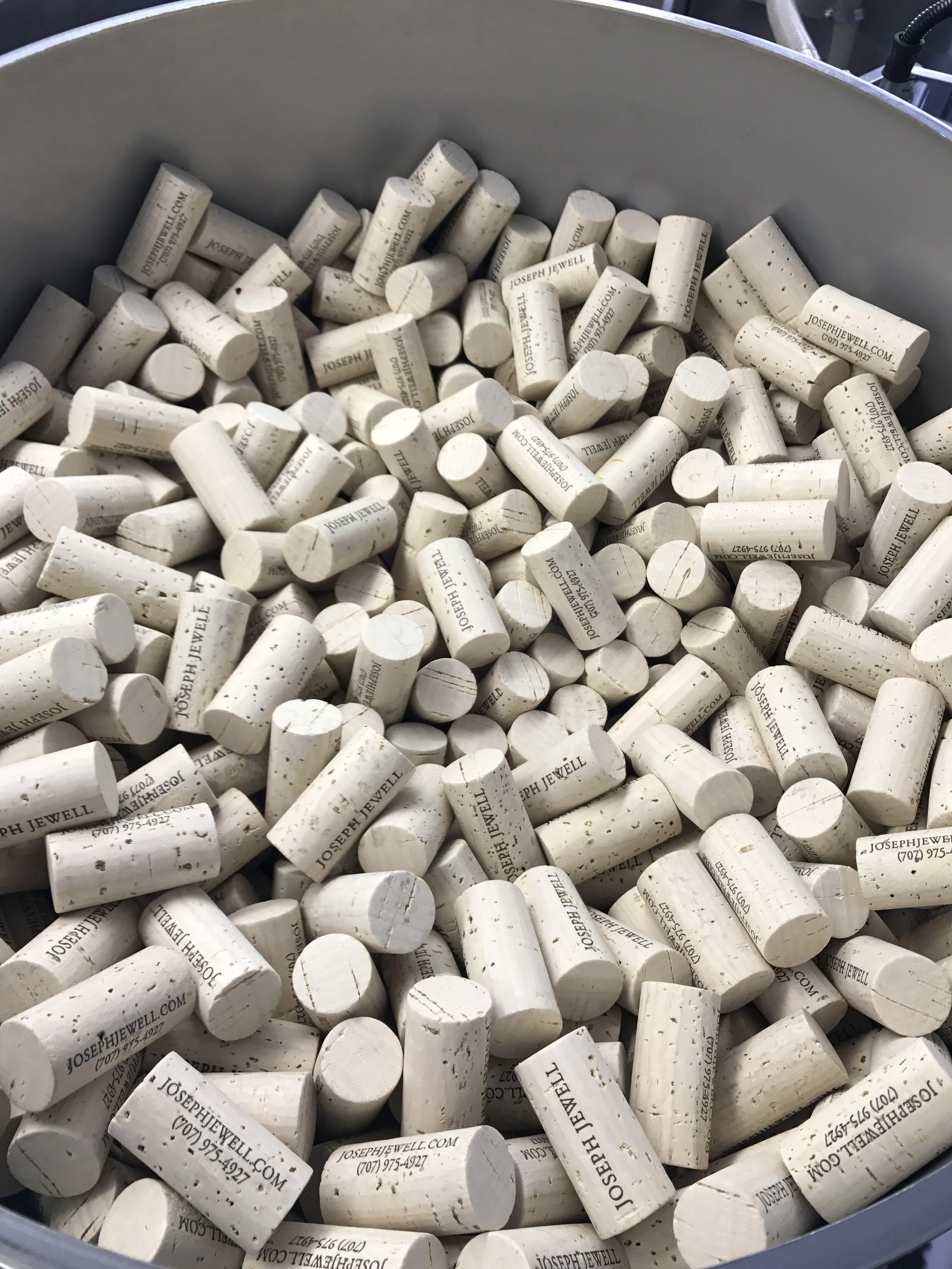A large container filled with numerous white chalks, each branded with 'JOSEPHJEWELL.COM' and contact information, used for marking or writing.