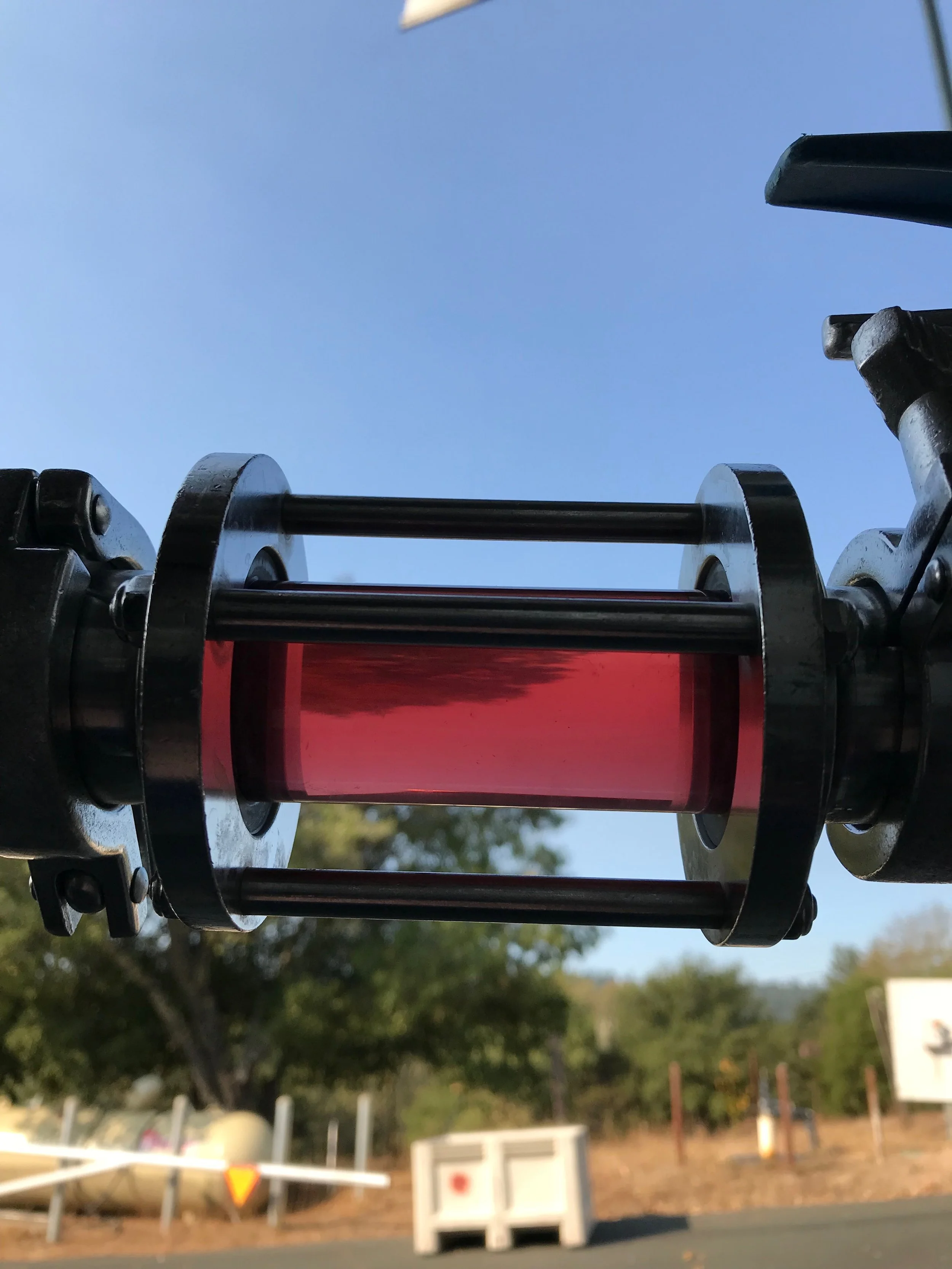 Close-up of a model rocket engine displaying its metallic parts and red engine casing, with a clear blue sky in the background.