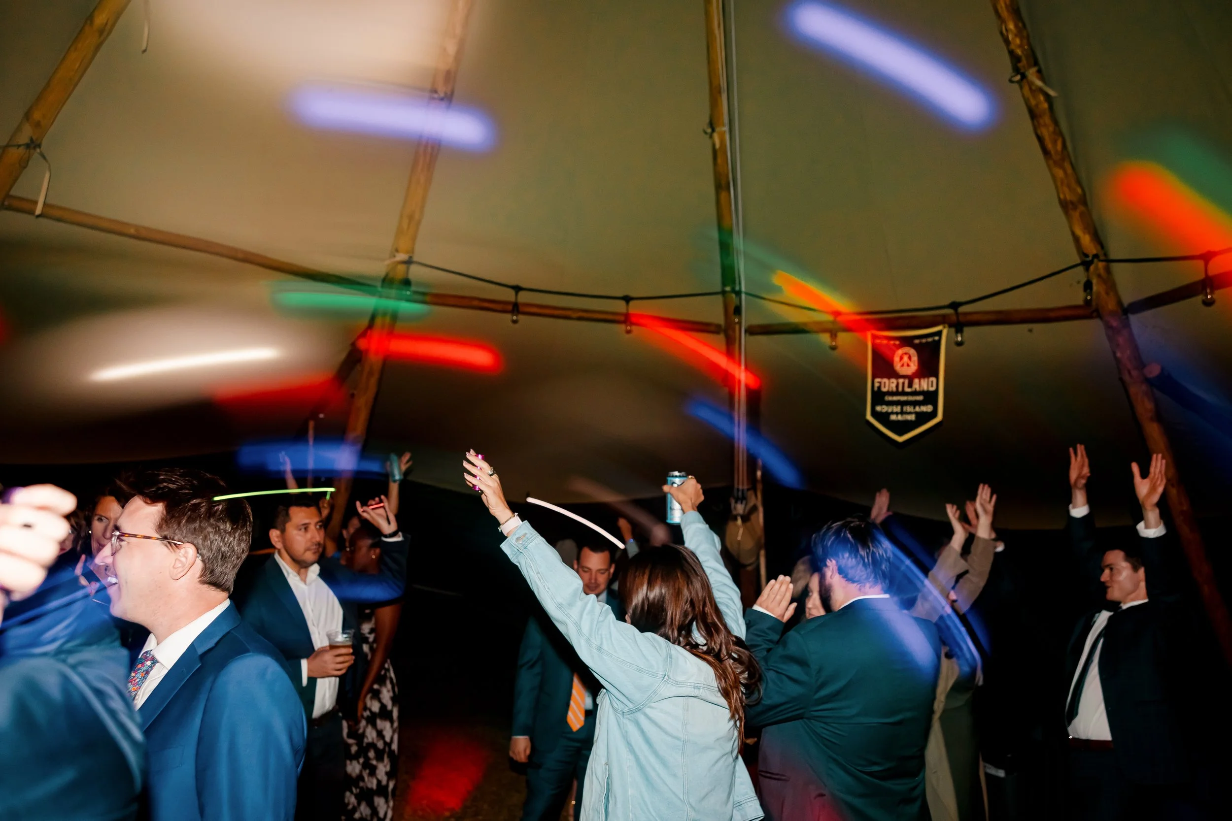 People dancing and celebrating inside a tent at an event with colorful lights and a Portland banner hanging from the ceiling.