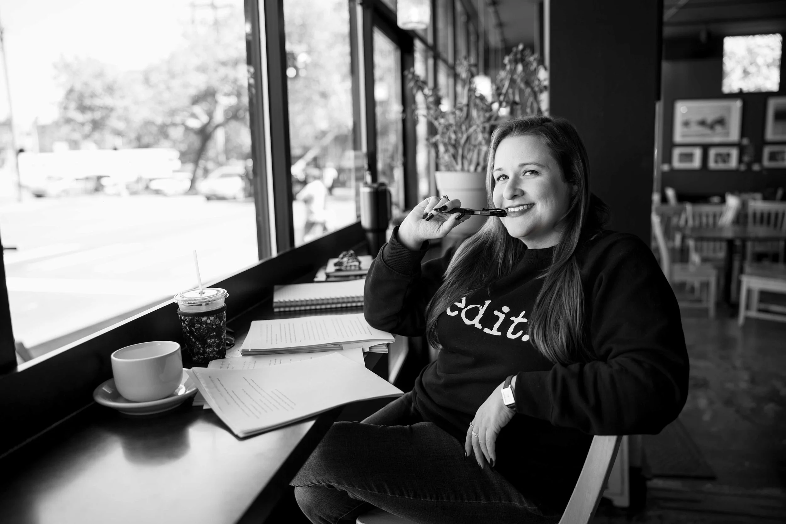 Woman writing with a pen while working on documents at a cafe table with coffee and a smoothie
