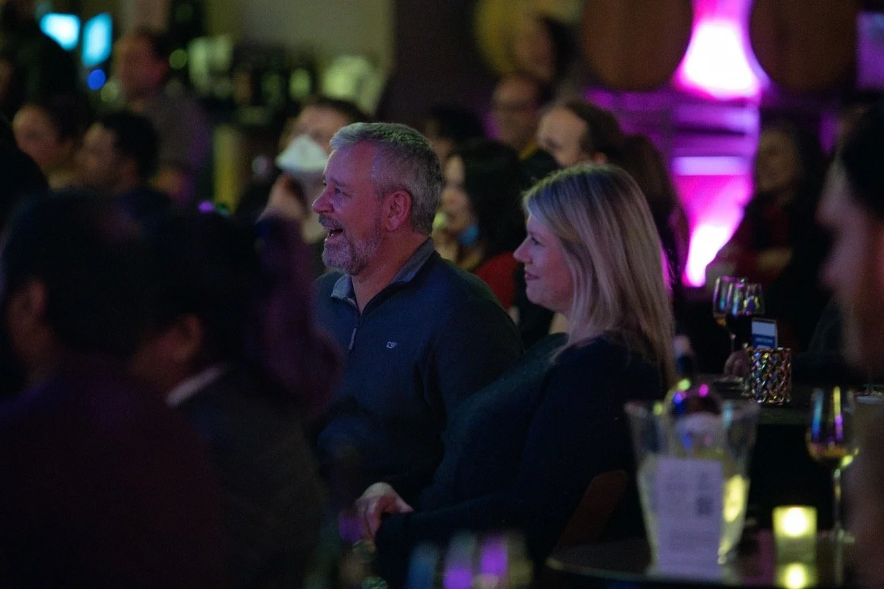 Audience enjoying live event at a bar with dim lighting and decorations.