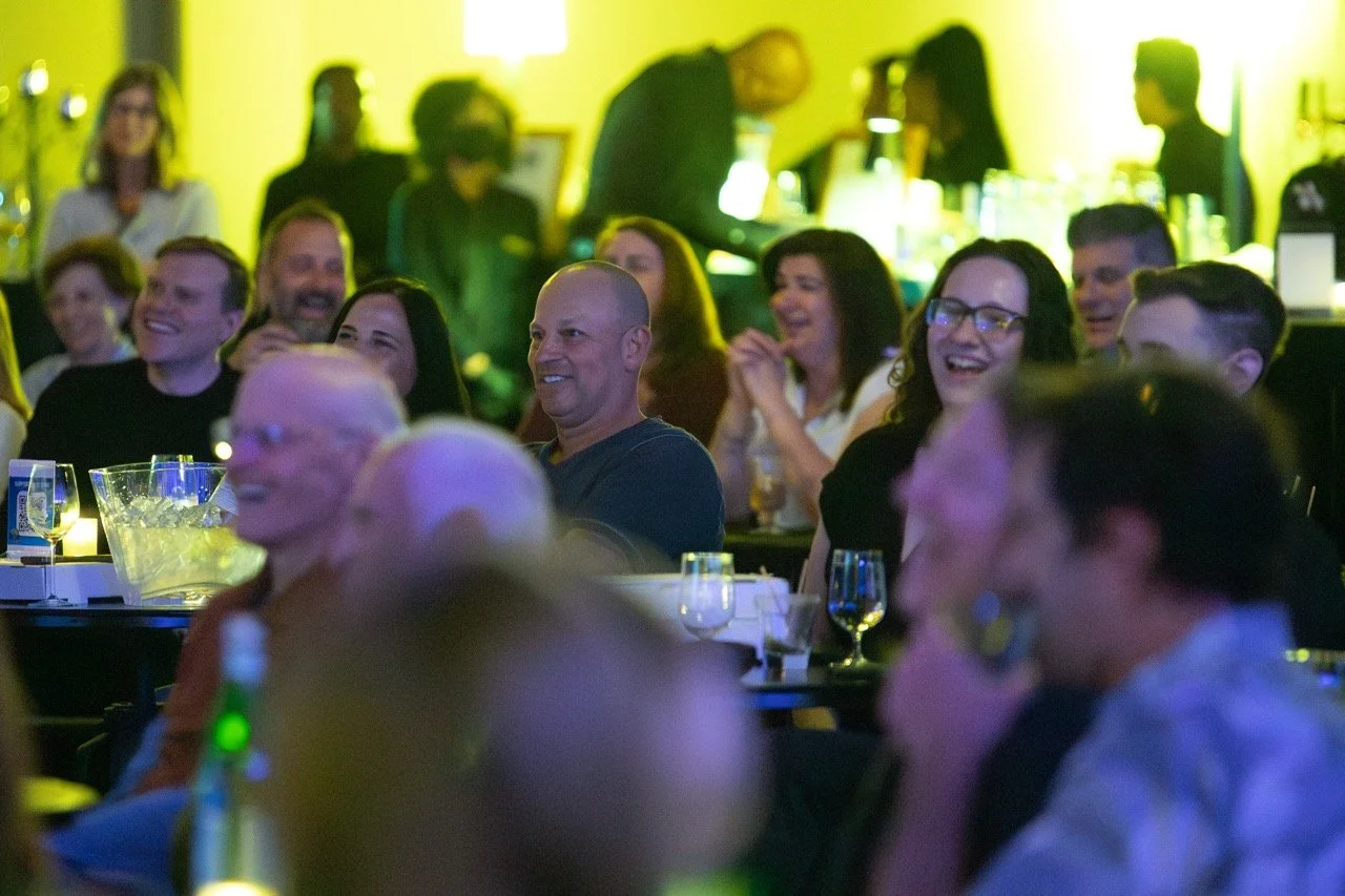 Audience laughing at an event with drinks