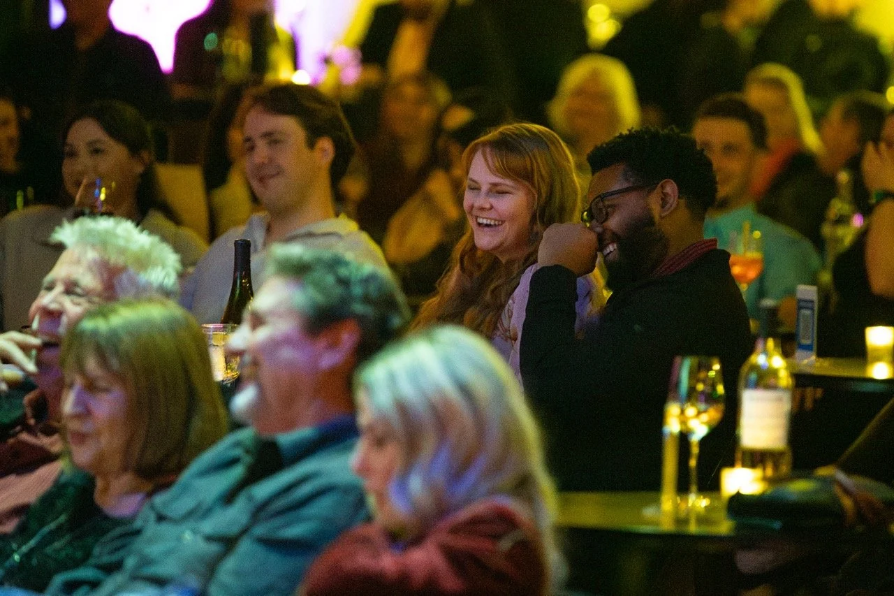 Audience laughing and enjoying a performance at a comedy club.