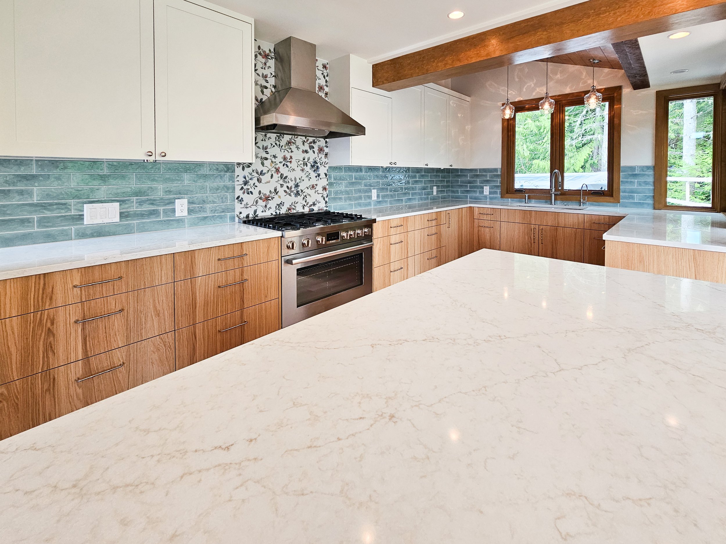Renovated kitchen in a Whistler home with modern cabinetry, stone countertops, and natural wood finishes