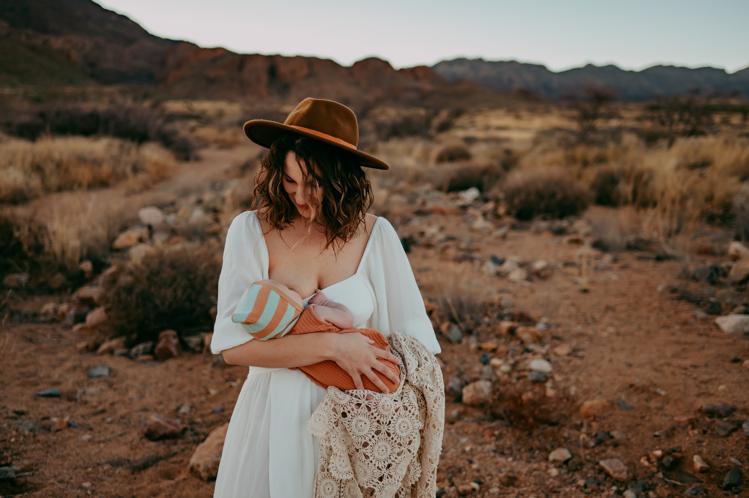 mom nursing her newborn baby by the mountainside