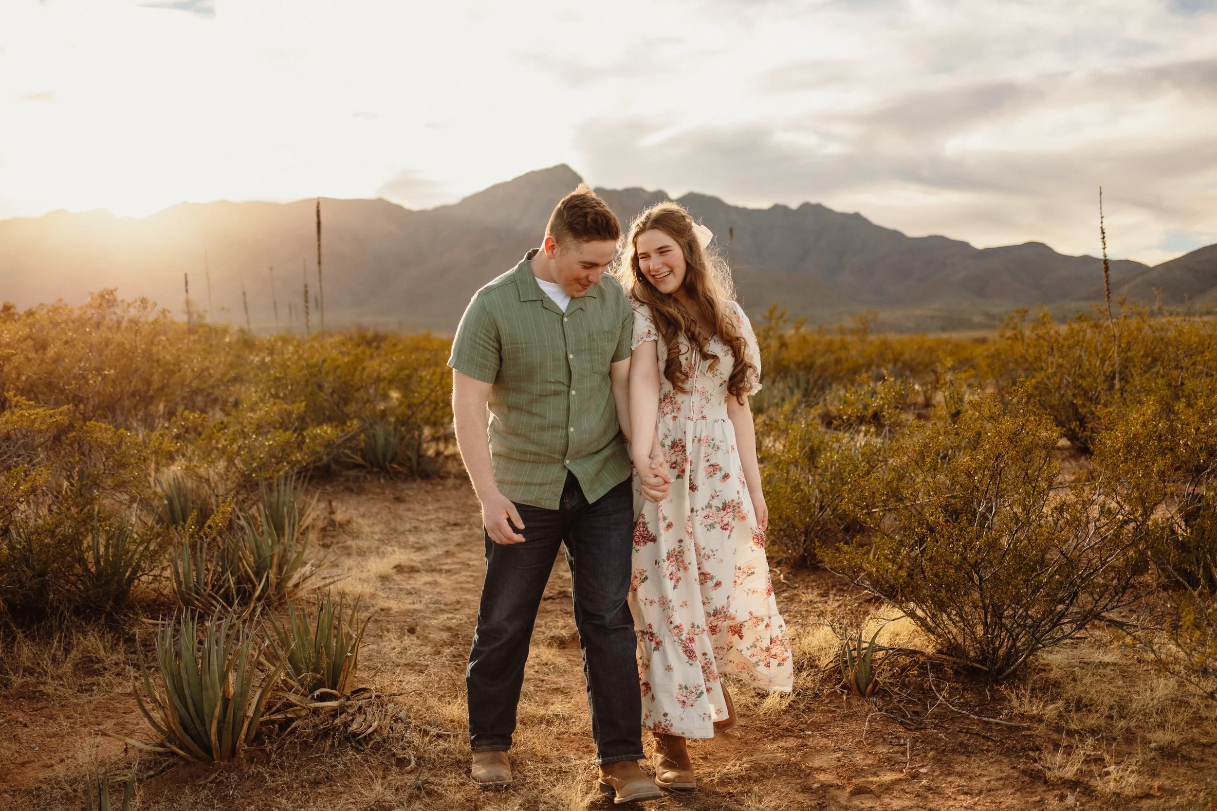 a couple walks together hand in hand smiling at each other, engagement pictures in El Paso, TX