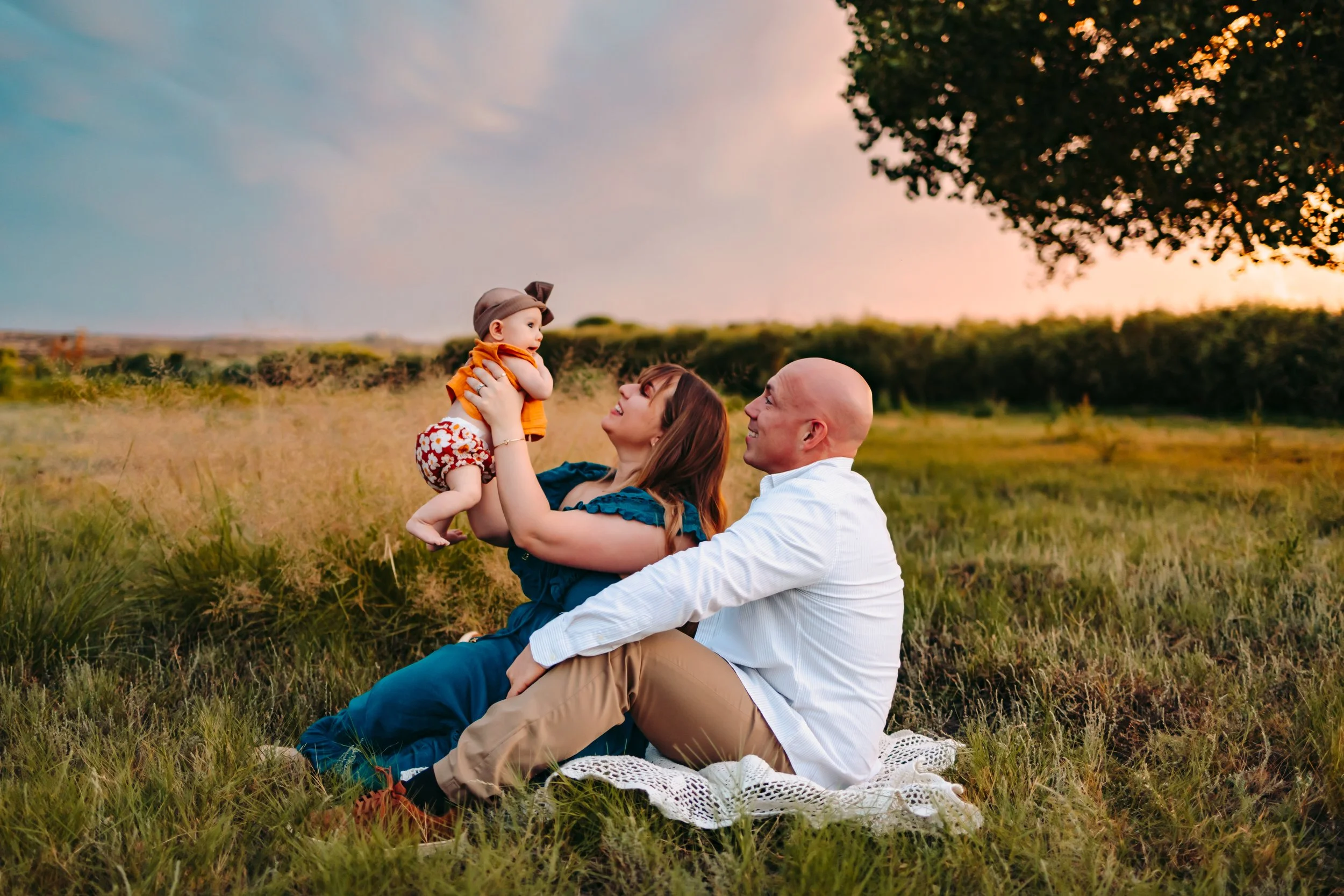 couple in a field lovingly playing with their baby