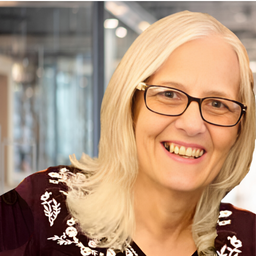 Smiling woman with glasses and blonde hair in embroidered top