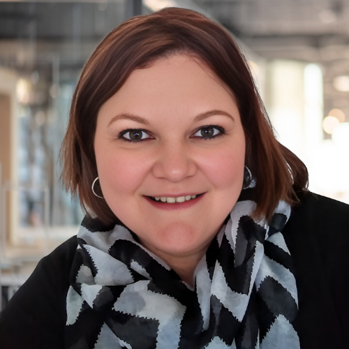 Smiling person with short brown hair wearing a patterned scarf