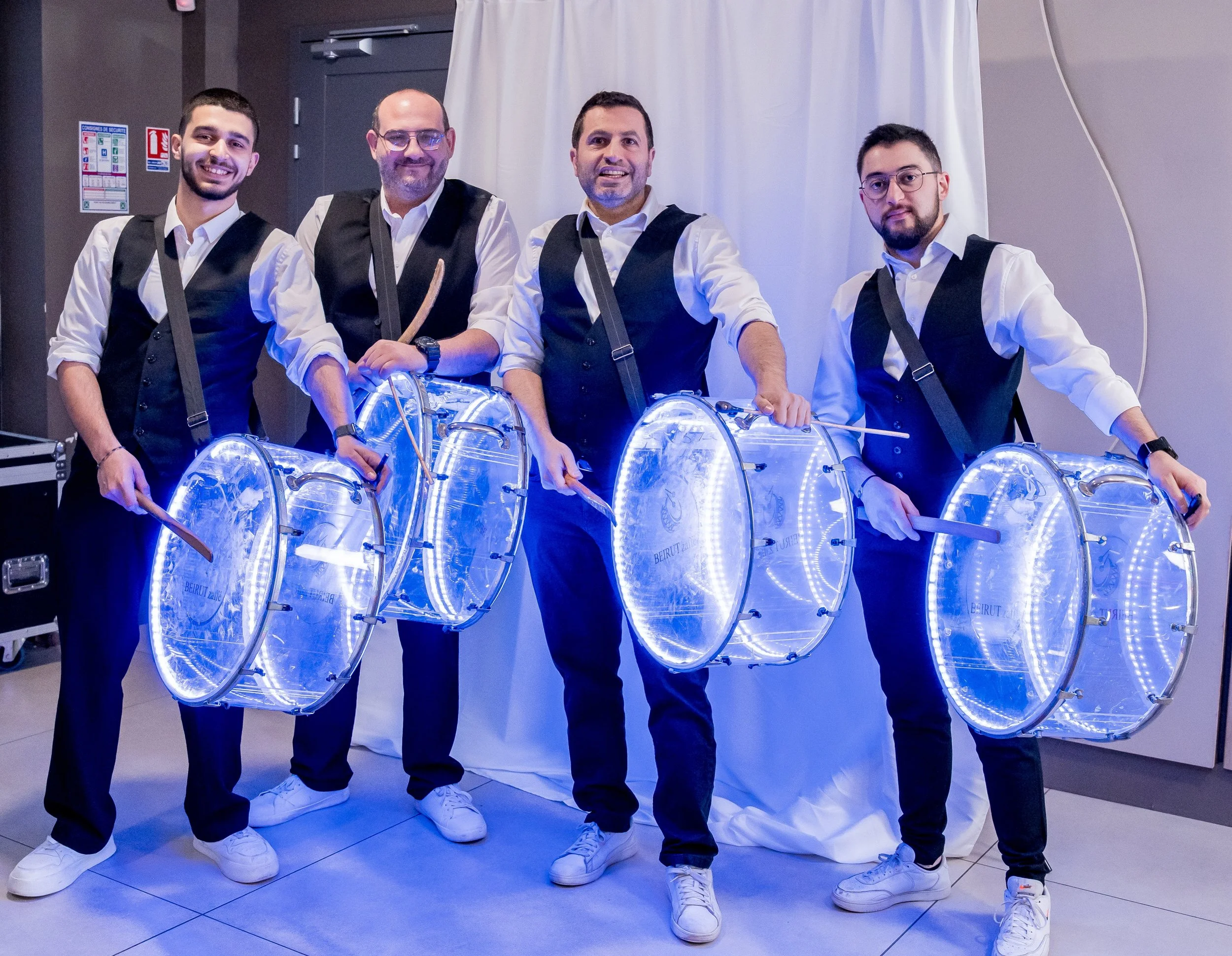 Cinq danseurs percussionnistes de l'équipe hommes de Beirut Zaffé habillés en costumes modernes portant des tambours lumineux à LED.