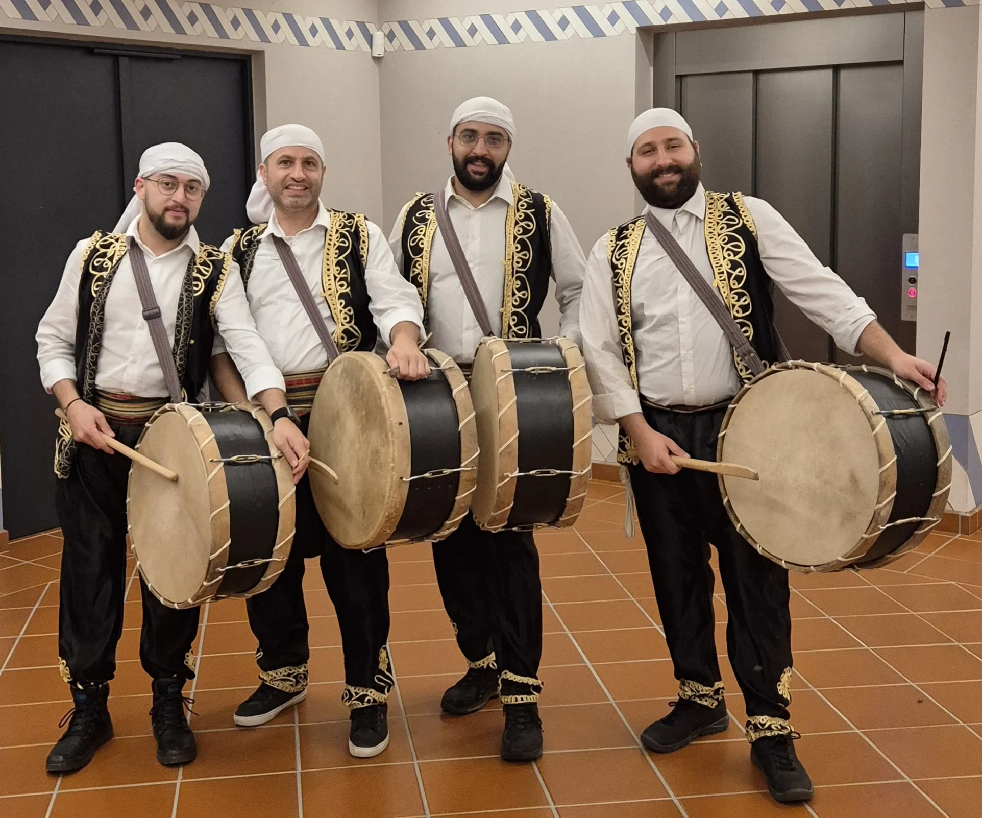 Cinq danseurs percussionnistes de l'équipe hommes de Beirut Zaffé habillés en costumes traditionnels portant des tambours libanais.