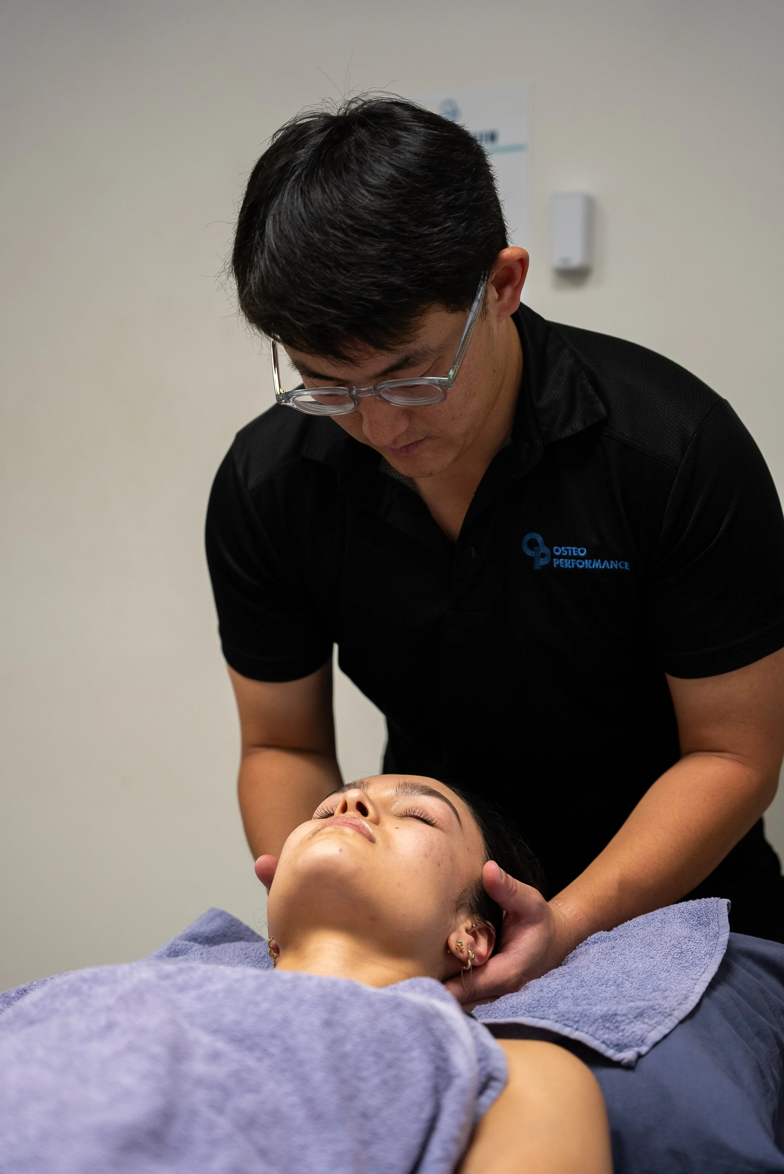 A person receiving a massage or chiropractic adjustment from a professional in a clinic setting.