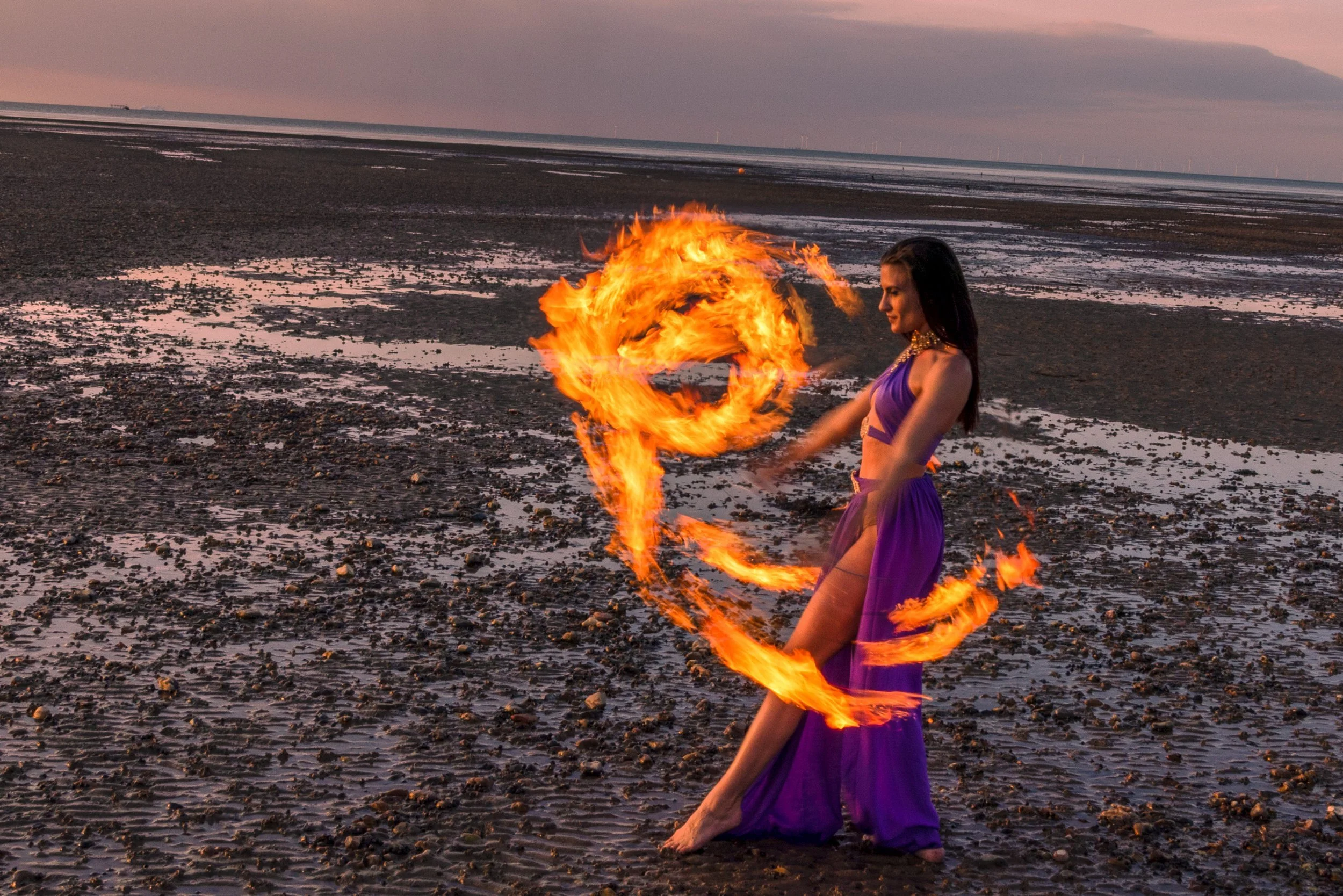 A circus performer spinning fire at the beach. (Taken by Faversham Photography)