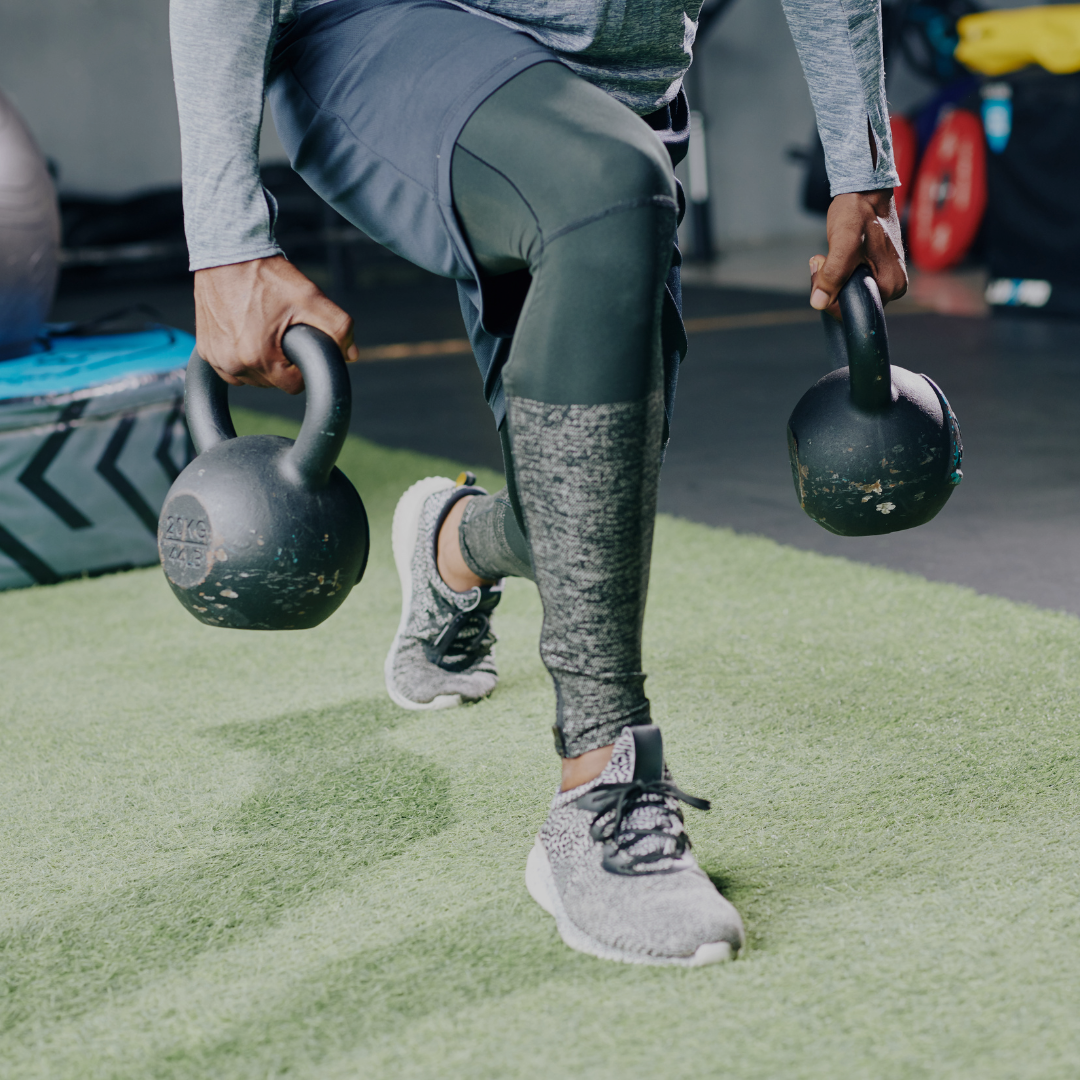 Person performing a balance exercise with kettlebells in a gym