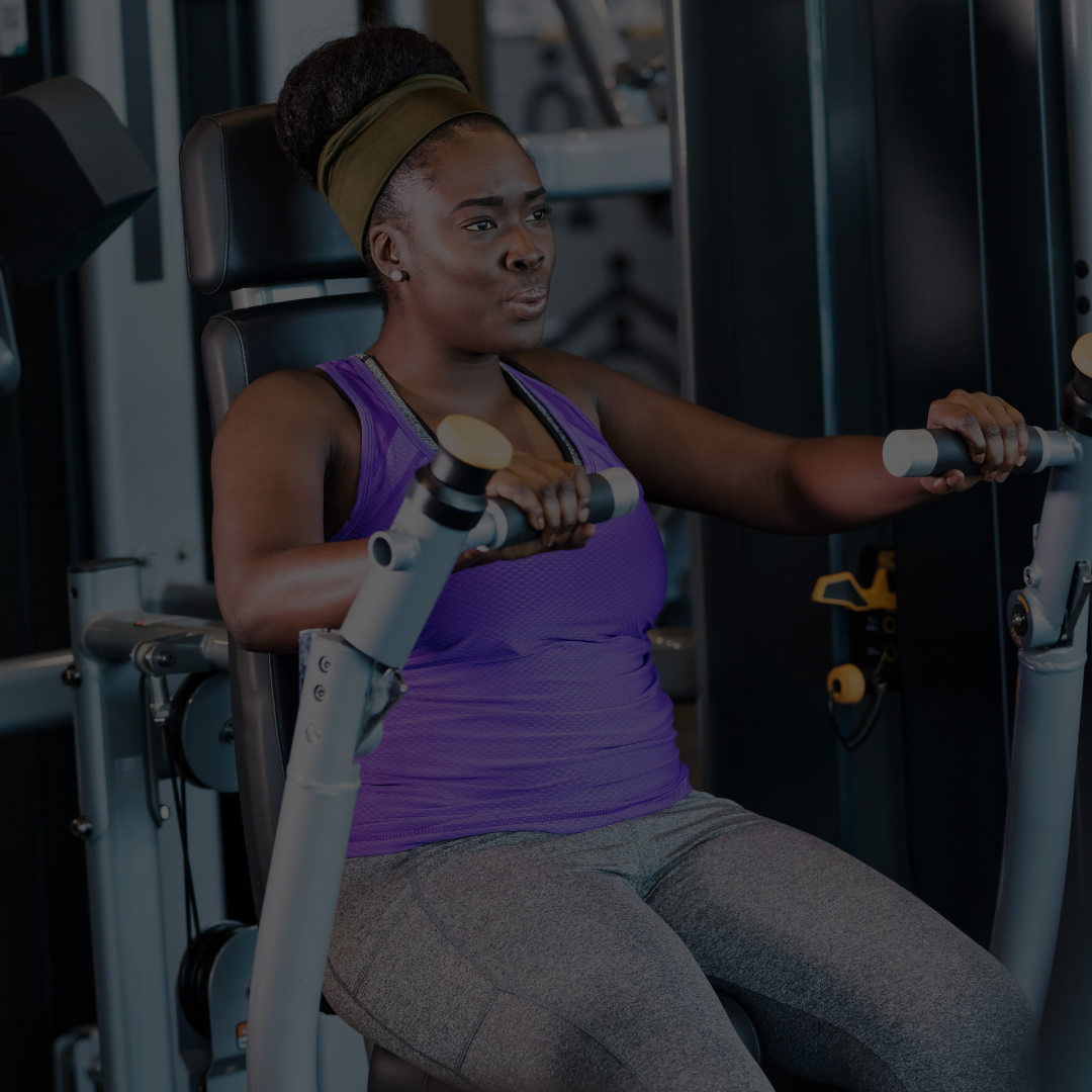 A woman exercising on a chest press machine in a gym.