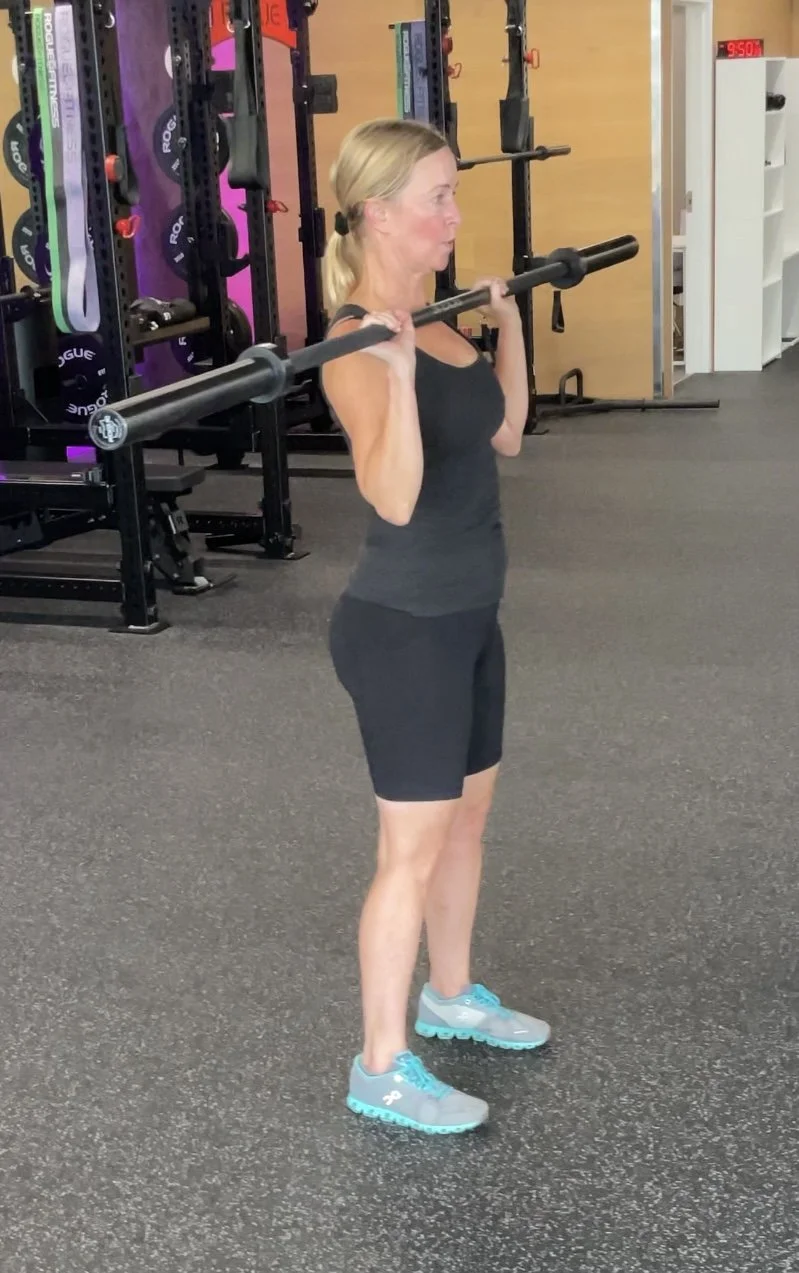 Woman lifting a barbell in a gym.