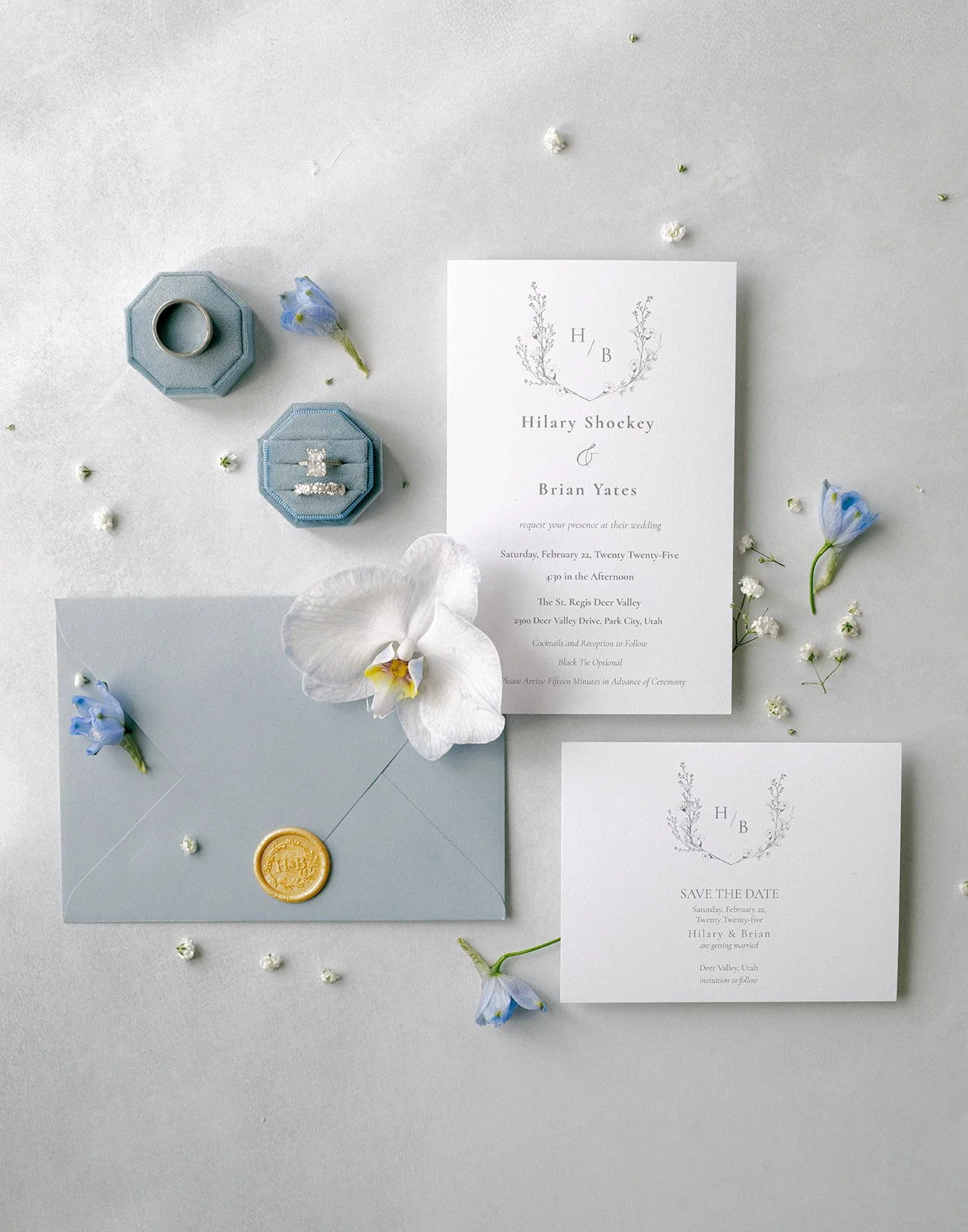  Custom escort card wall with gray and white envelopes and gold wax seals, next to a winter floral arrangement at St. Regis Deer Valley. 