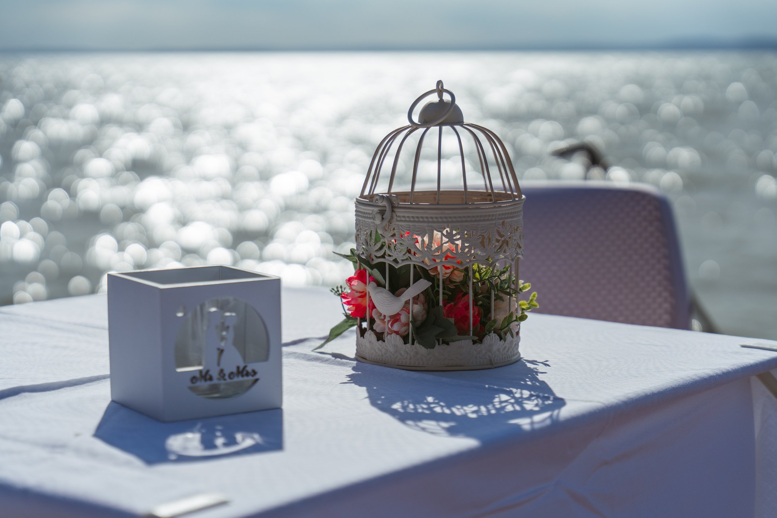 Esküvői kellékek, virágos kalitka a Balatonparton esküvői fotózásnál.