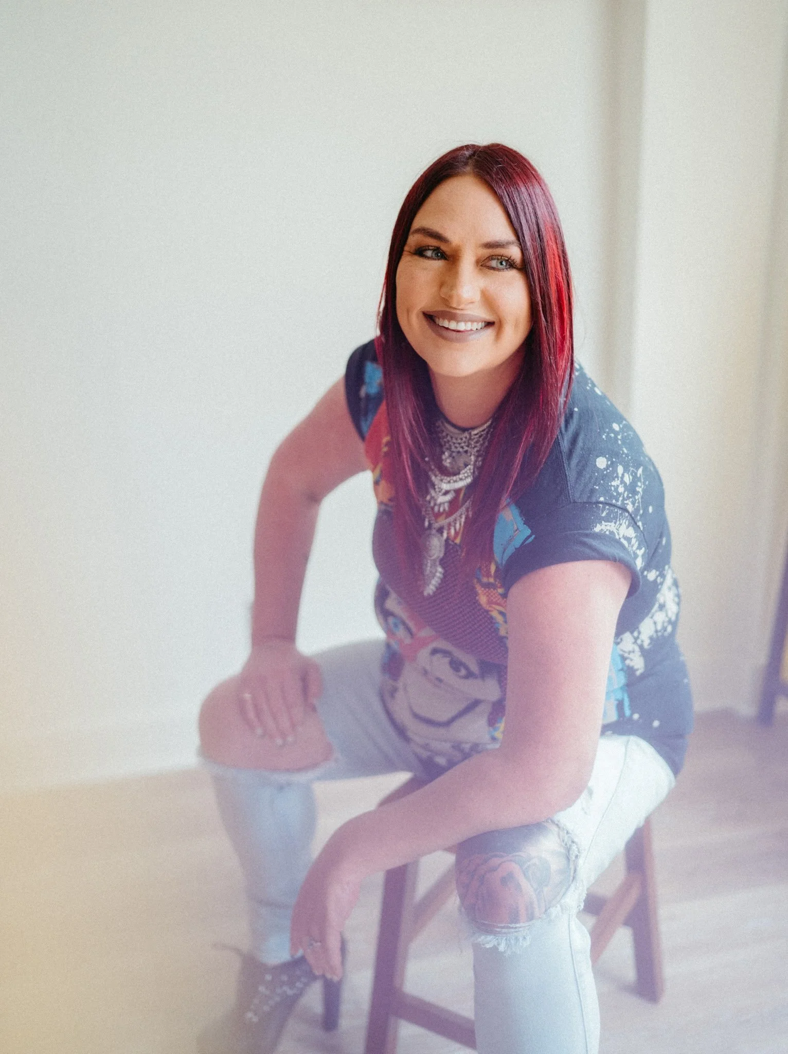 Salon stylist with sleek deep red hair and vivid red highlights, smiling in in a photo studio in appleton, wisconsin.