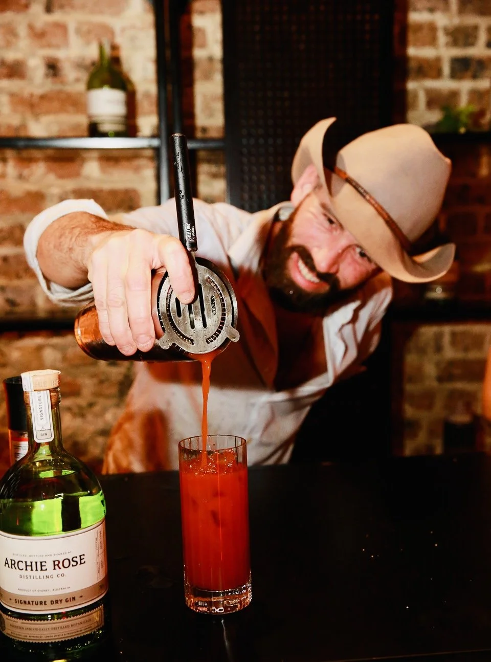 Whisky Pete mid-pour, creating a bloody mary cocktail with flair and focus.
