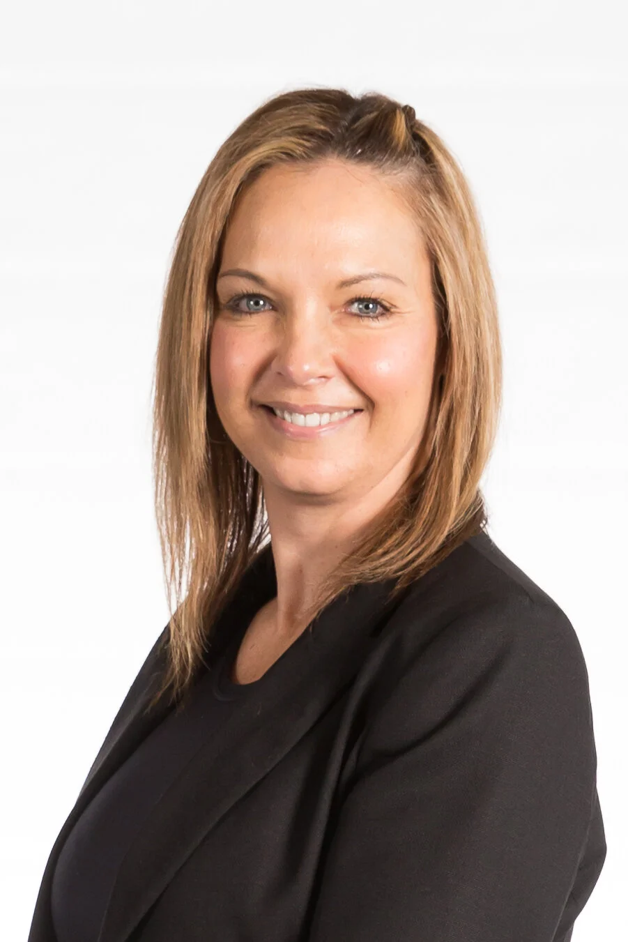 Professional woman with shoulder-length blonde hair smiling, wearing a black blazer, against a white background.