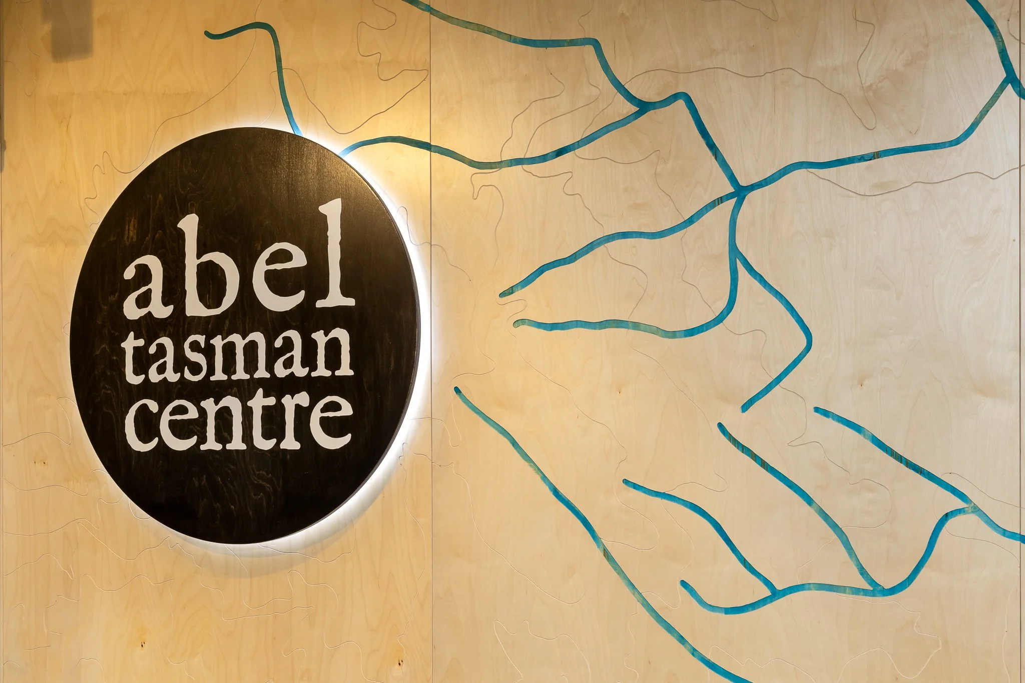 Sign for Abell Tasman Centre with a map of waterways on a wooden wall.