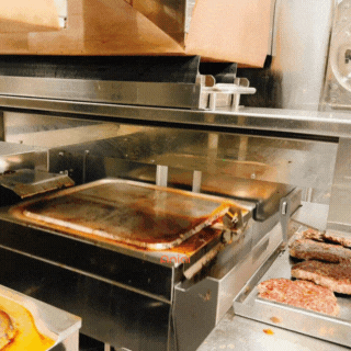 The in-built spatula becomes a scraper to clean the griddle after the patties are cooked. The automation is at play here, where the spatula is scraping the griddle and pushing the grease to the oil bucket, making it ready for the next batch.