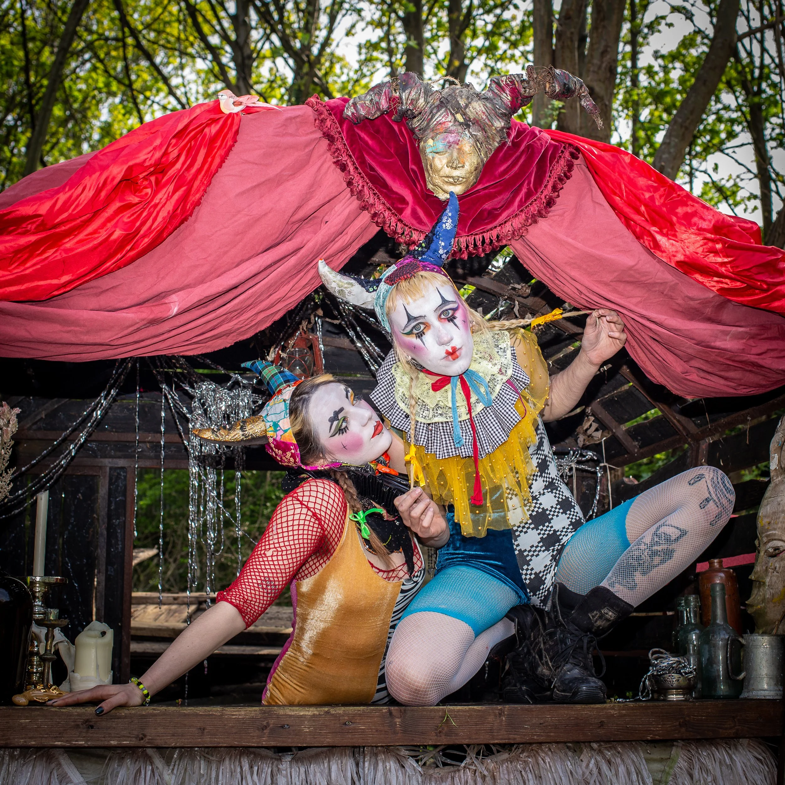 two girls dressed in clown costumes, neck ruffs and devil hats