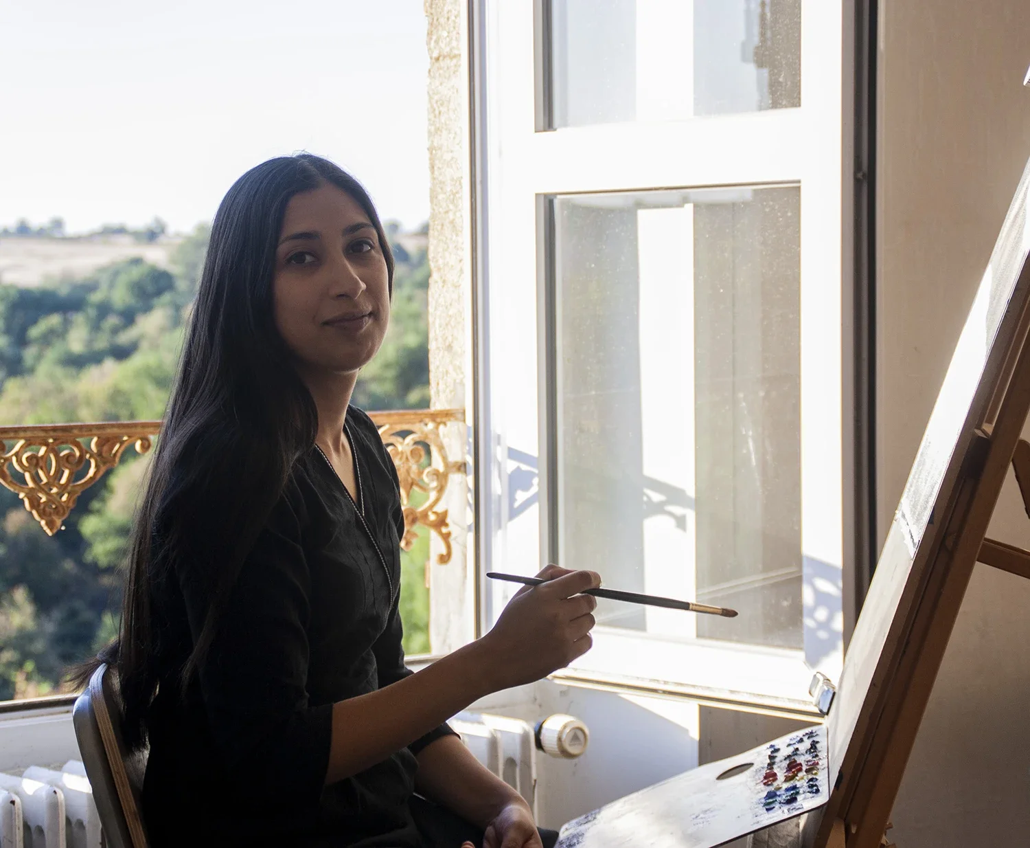 Portrait artist Swathi Madike painting at an easel, during her classical realism training in France