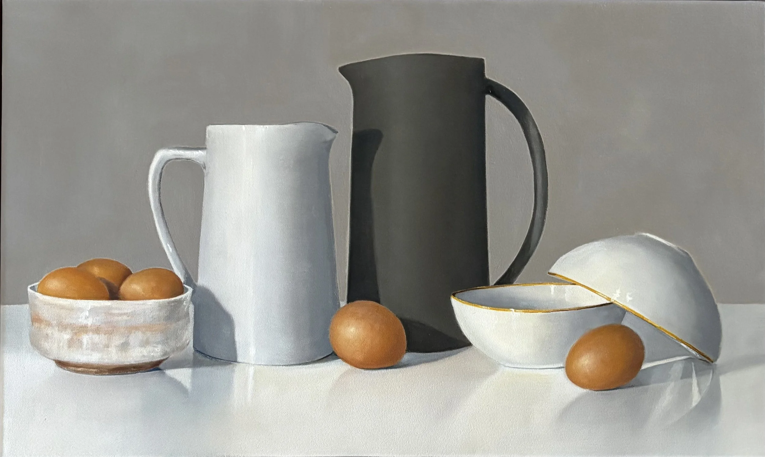 A still life painting with two ceramic pitchers, a bowl of brown eggs, a couple of loose eggs, and  two bowls with  gold rim on a white surface against a grey background.