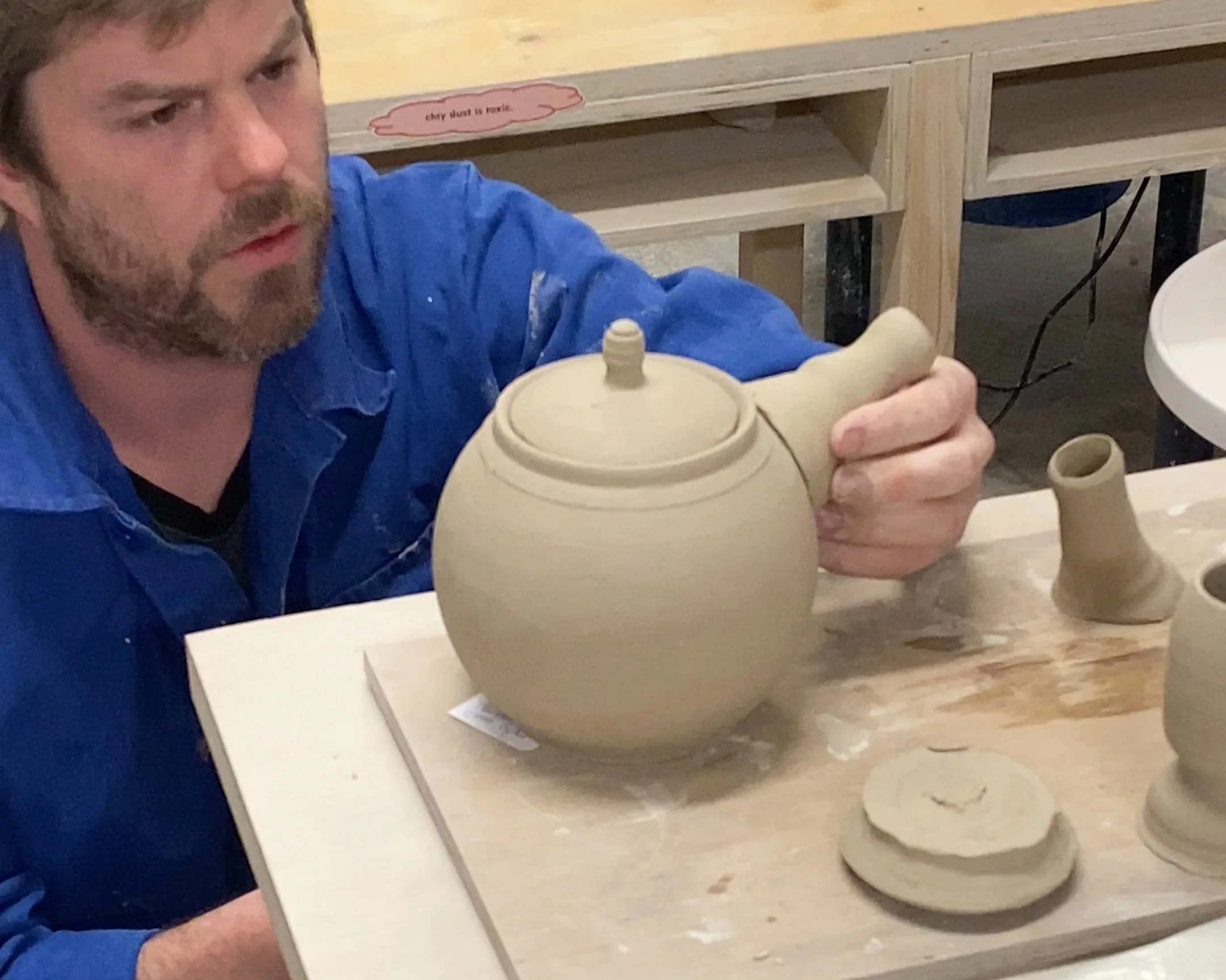 man inspects ceramic teapot build 