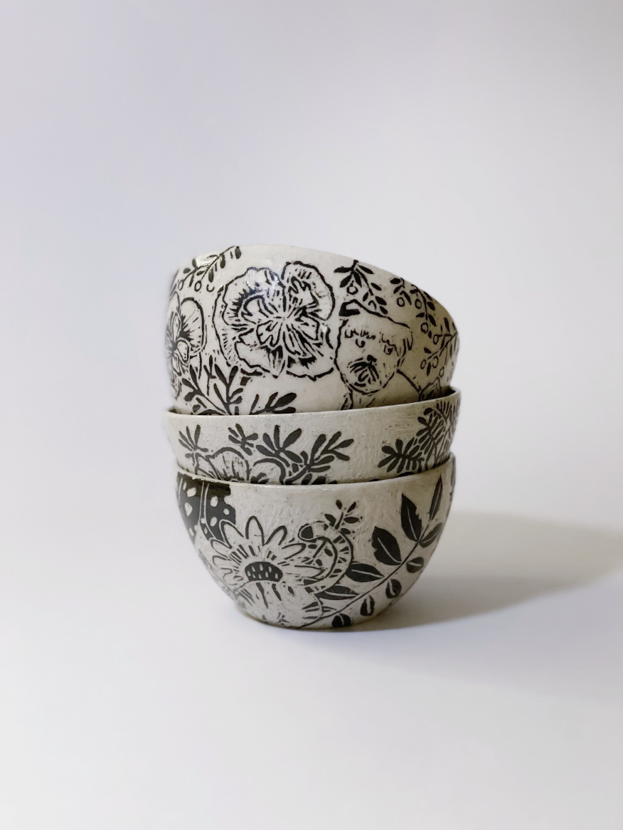 Three small bowls with black floral patterns stacked on top of each other on a white background.
