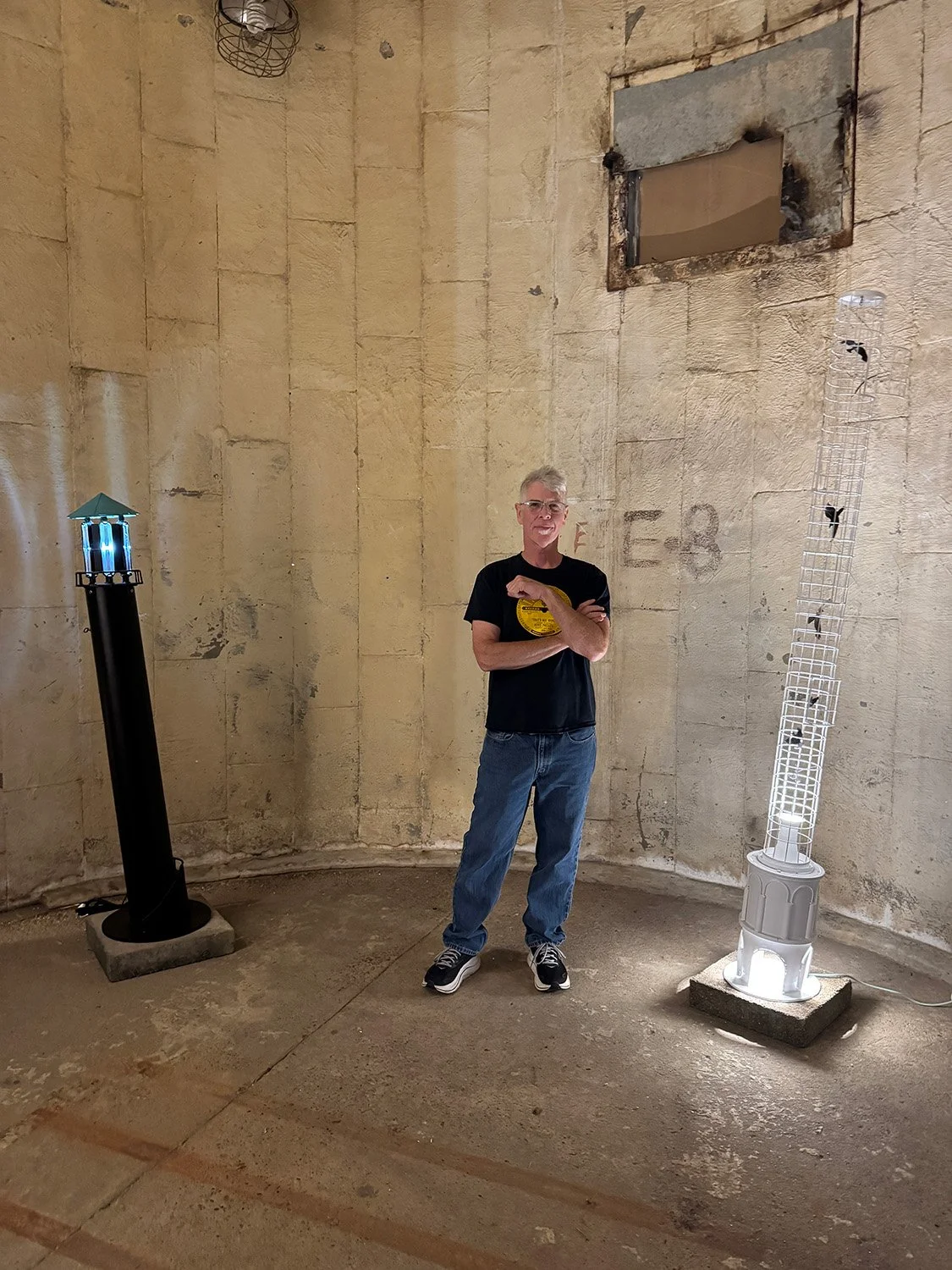 Tim Glover by his artwork "Lighthouse" and "Leaning Tower of Birds"