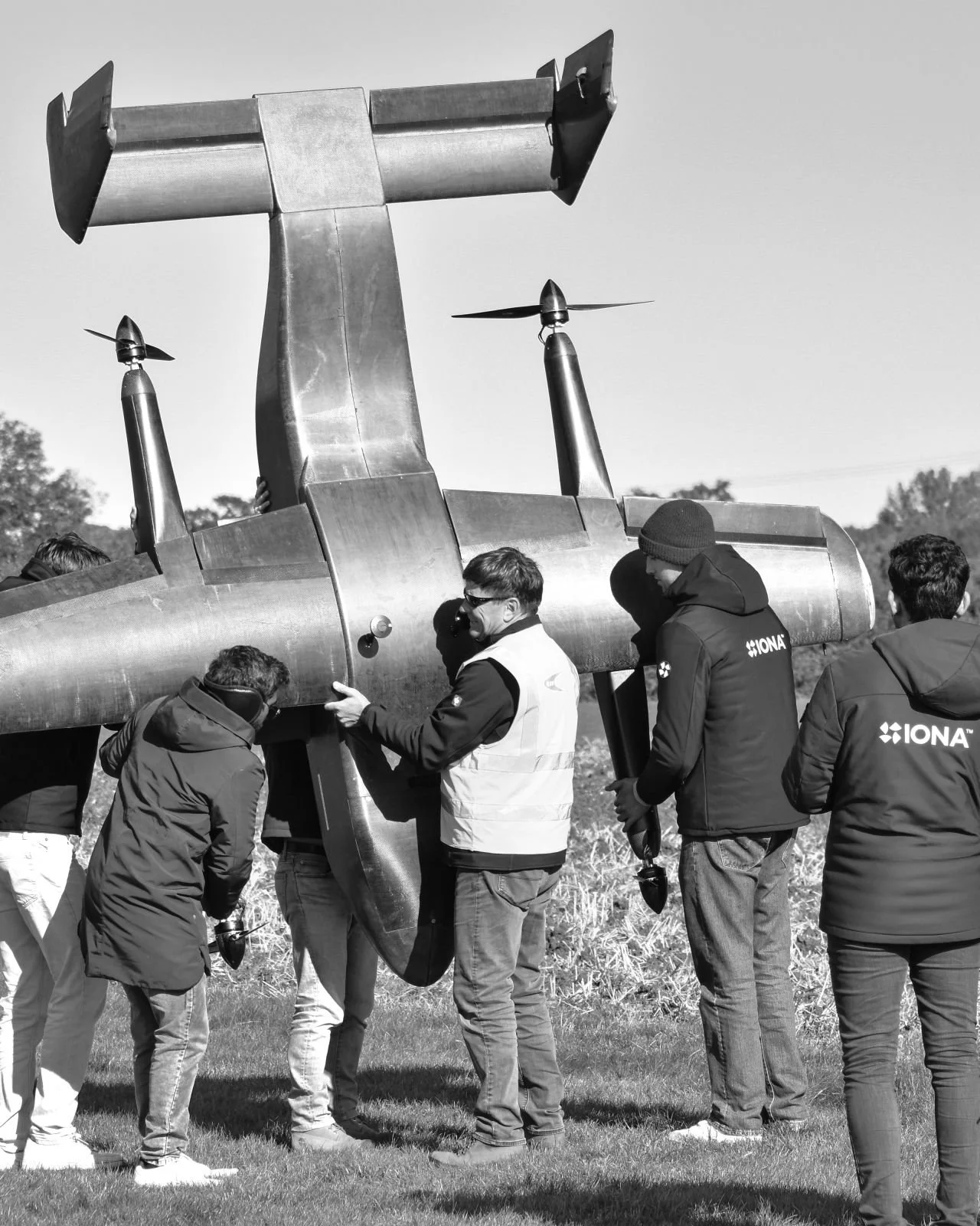 Group of people assembling or inspecting a large drone outdoors