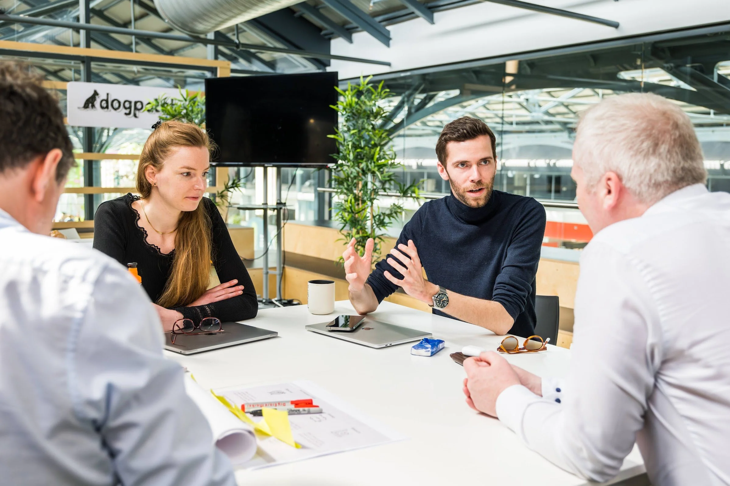 Group of people having a business meeting at a table with laptops and documents in a modern office setting.