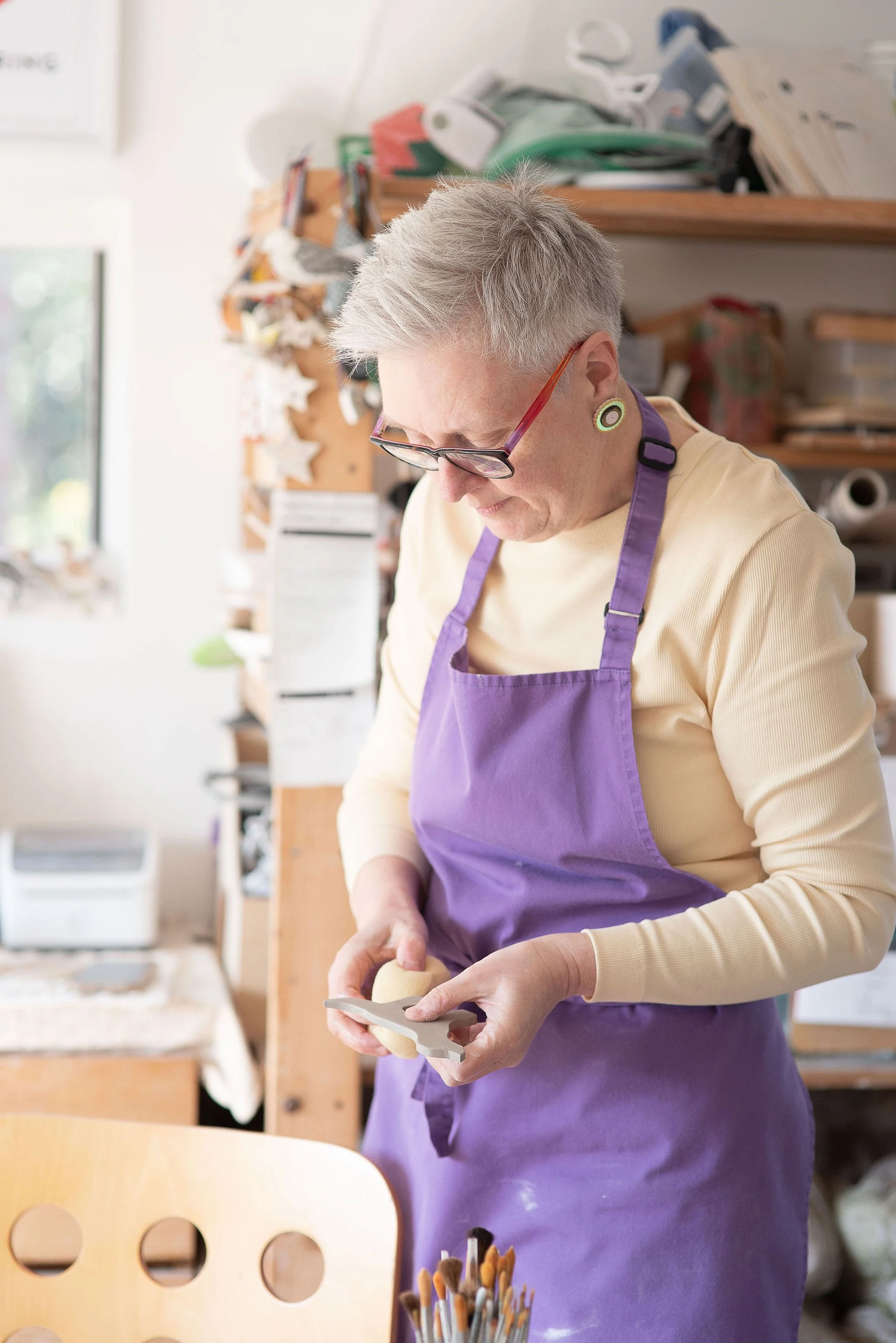 Woman fettling and cleaning a pottery piece ready for firing