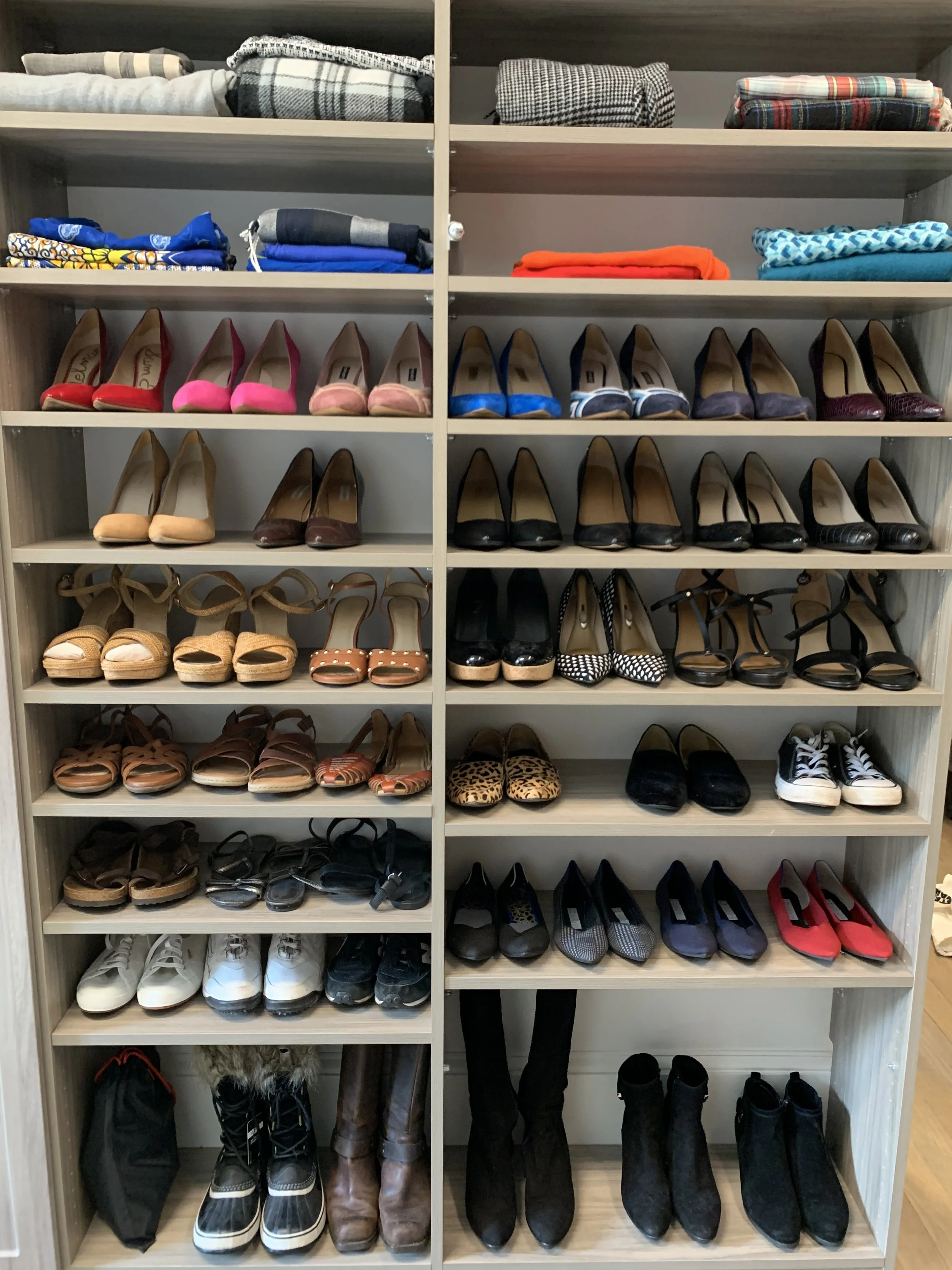 Organized closet in Atlanta, showing shoe wall with various pairs of women's shoe organization on multiple shelves, with clothes organized and folded on top closet shelf.