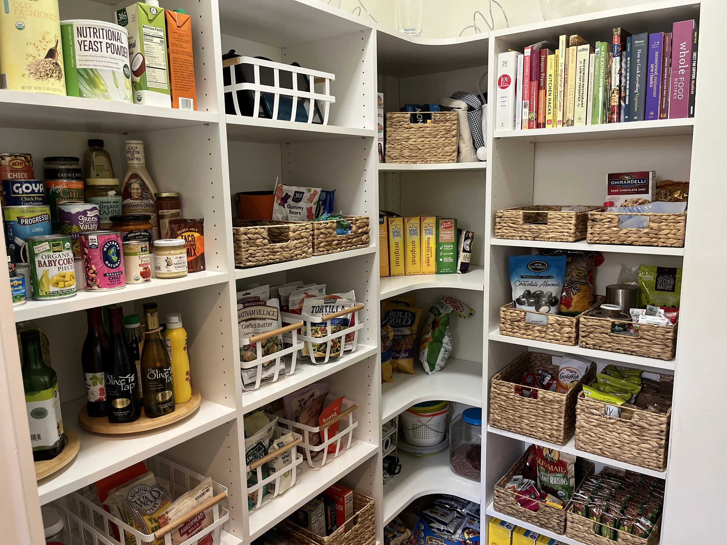 Organized pantry in Decatur, GA. Elegant organizing baskets contain food items, canned goods, snacks.