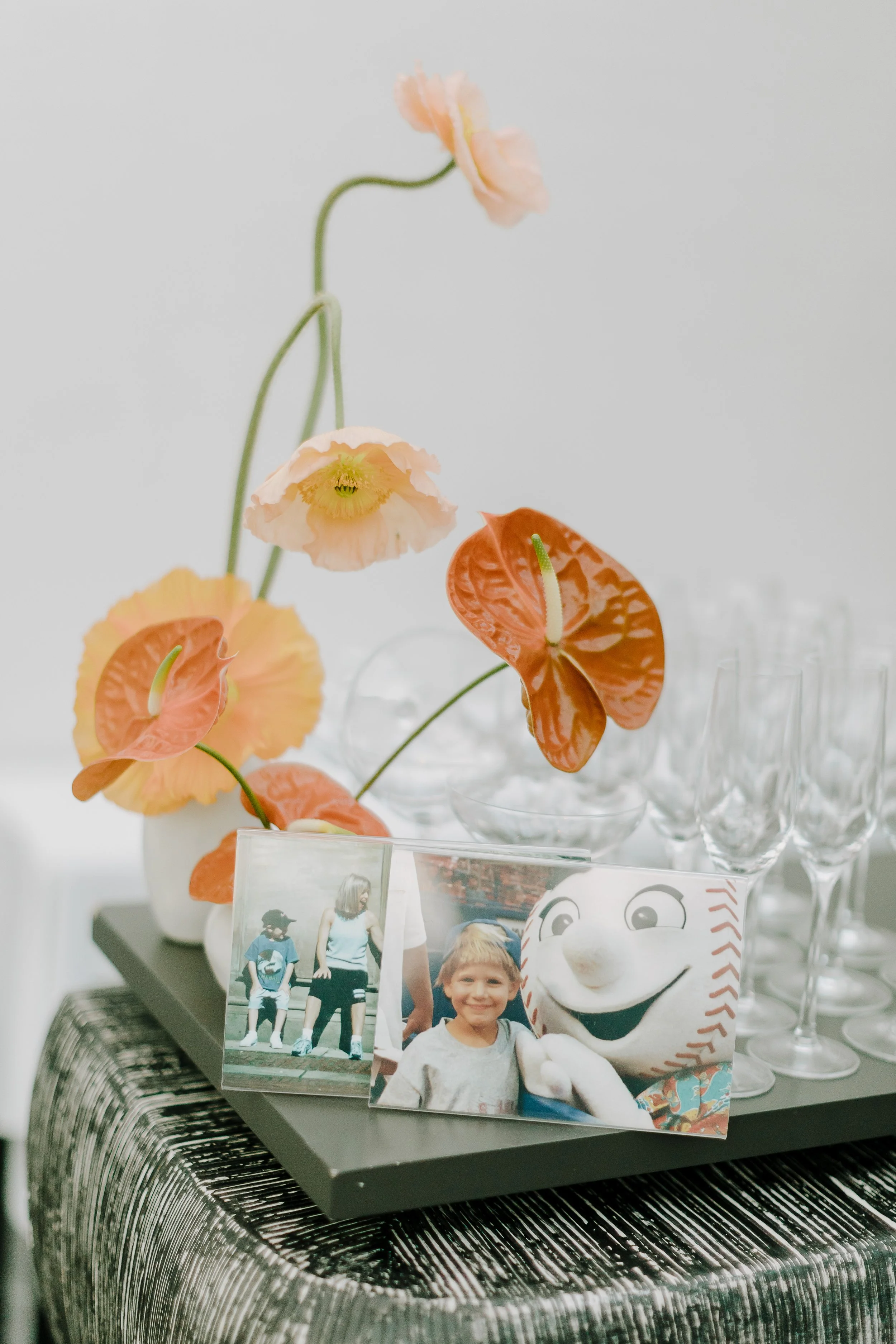 Decorative floral arrangement with peach-colored flowers and a photo collage on a table.