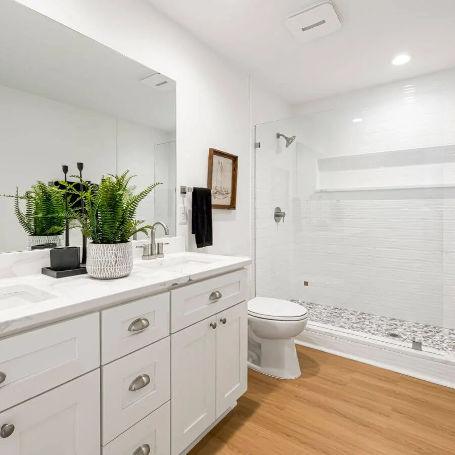 Bright, organized bathroom with a white vanity, clear countertops, and a clean, functional design.