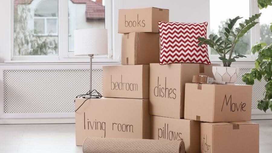 Moving boxes labeled for different rooms with home items nearby, representing an organized approach to preparing for a move.