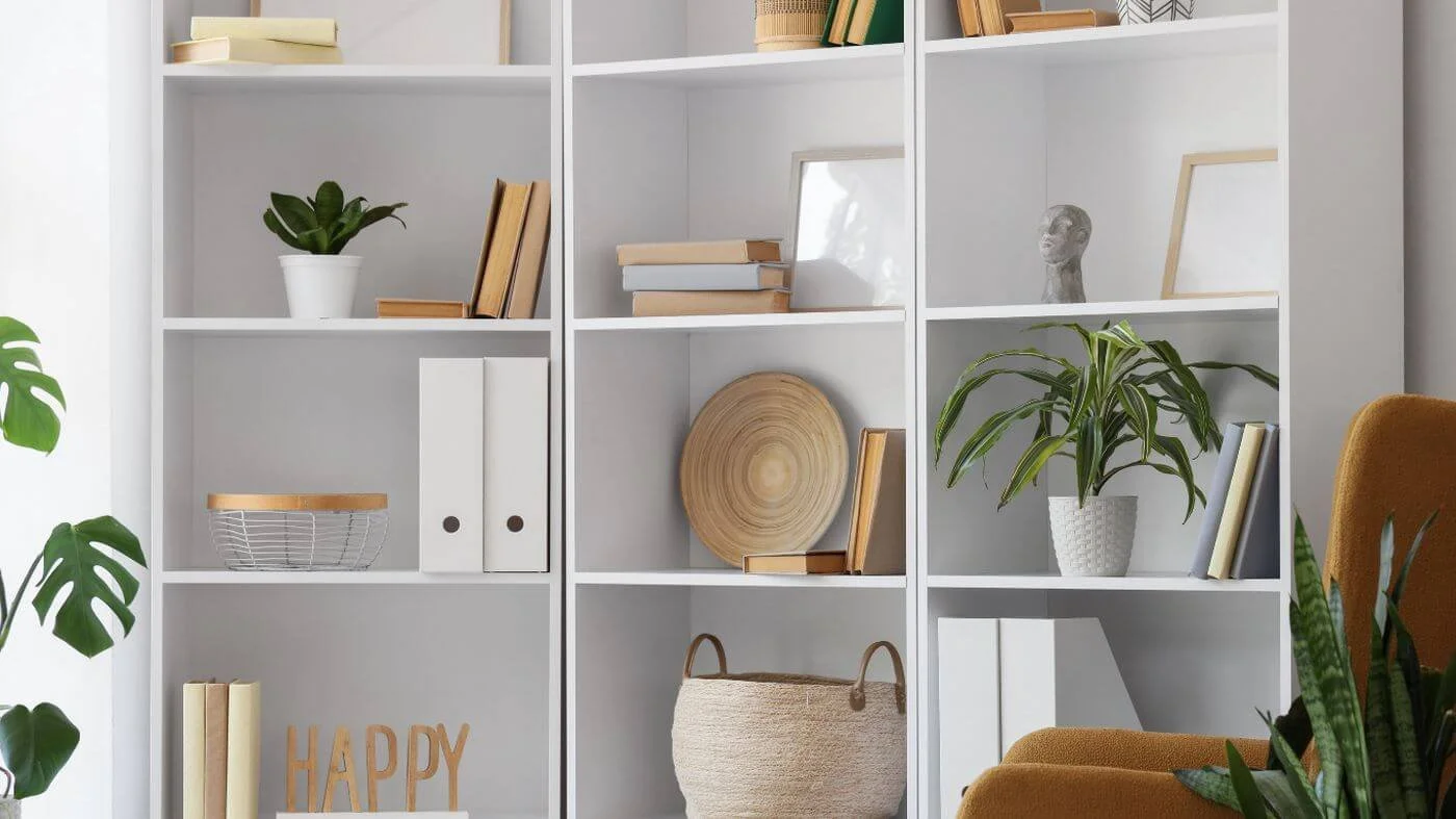 Bright bookshelf with a curated collection of books, decor, and plants arranged with open space to create an intentional and welcoming home.