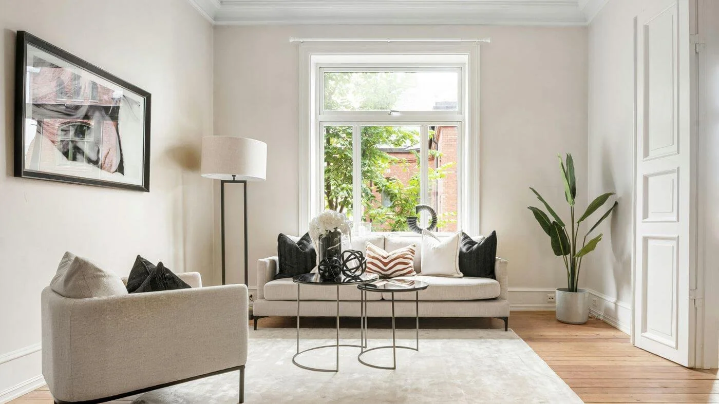 Bright, decluttered living space with comfortable seating, a floor plant, artwork, and natural light creating a calm and inviting home.