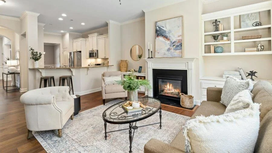 Decluttered whole home living space with a comfortable seating area, fireplace, and functional layout connecting the living room and kitchen.